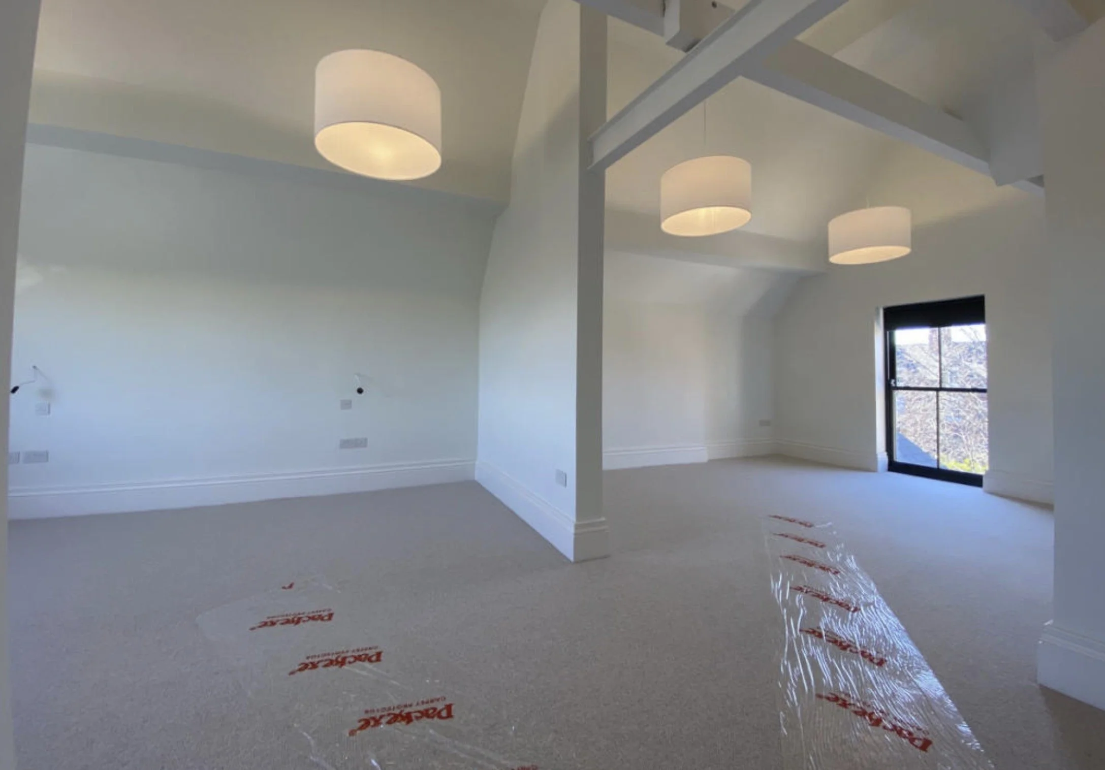 Second-floor guest suite with vaulted ceilings, exposed structural beams, contemporary lighting and generous accommodation.