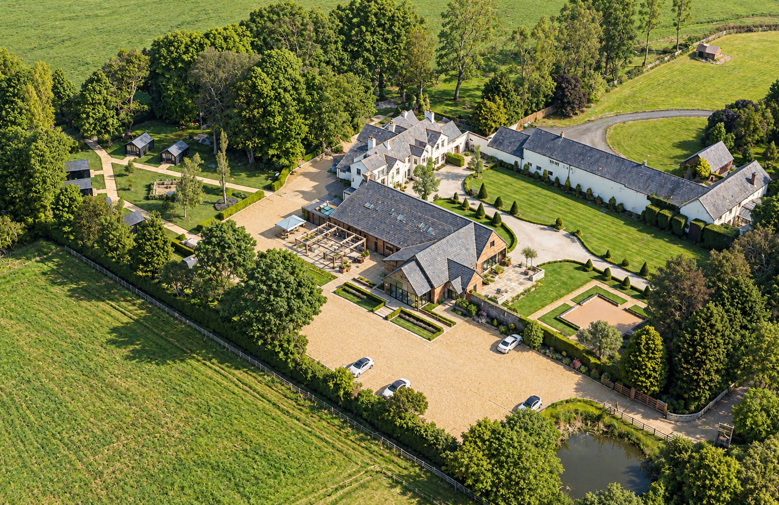 The River Barn, Poulton-le-Fylde, Lancashire — Aerial View — Aerial photograph showing the converted wedding venue, Mains Hall and surrounding buildings, with landscaped gardens, outdoor terraces and parking set within the Lancashire countryside.
