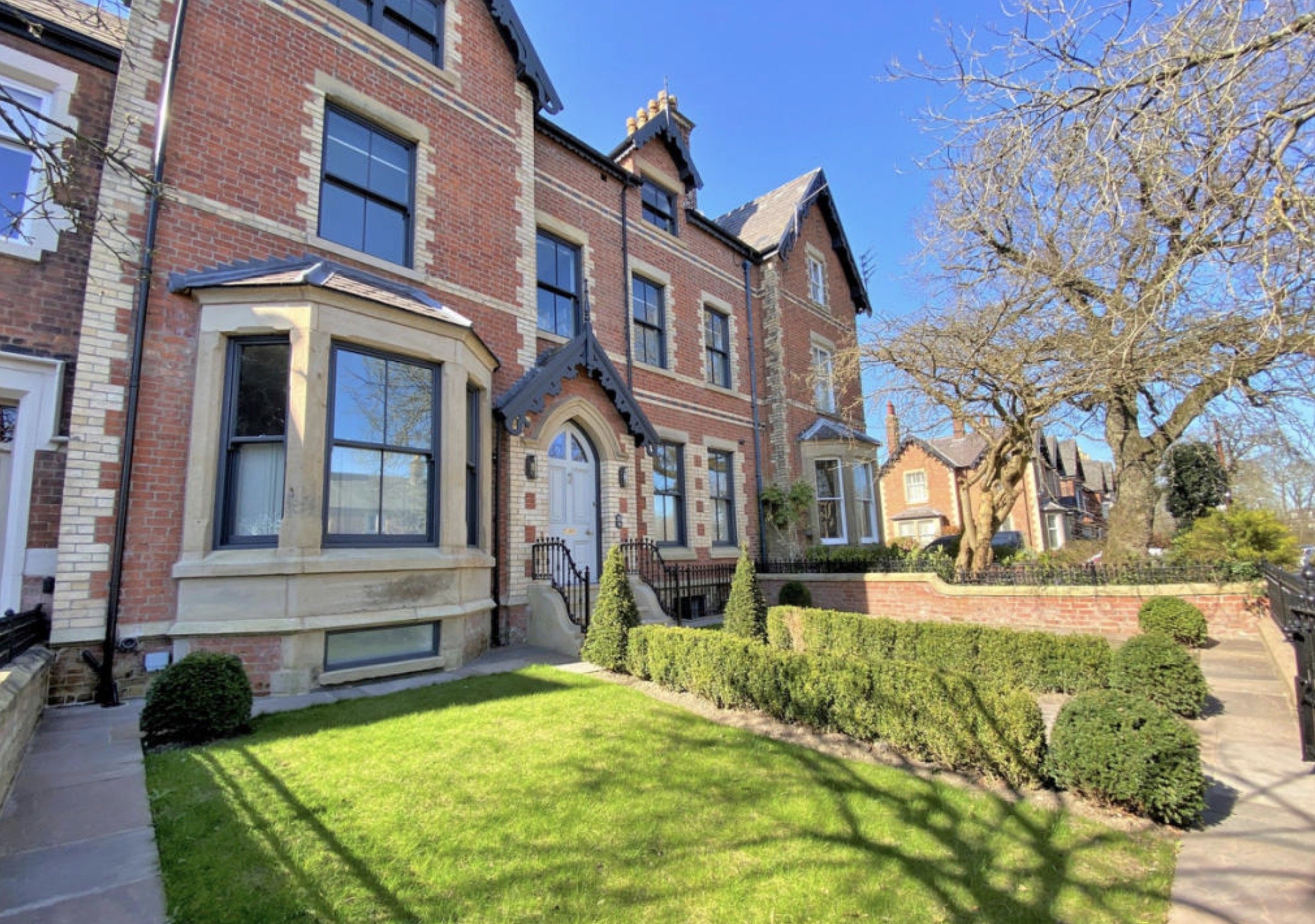 Period brick architecture overlooking the landscaped front garden.