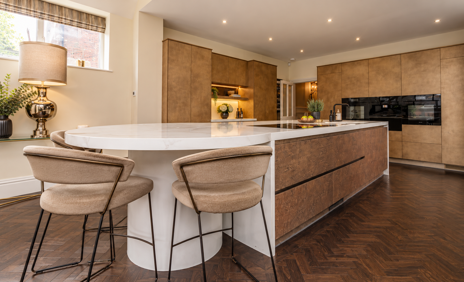 Kitchen — Bespoke contemporary kitchen featuring natural timber cabinetry, marble-effect worktops, generous island seating and integrated lighting.