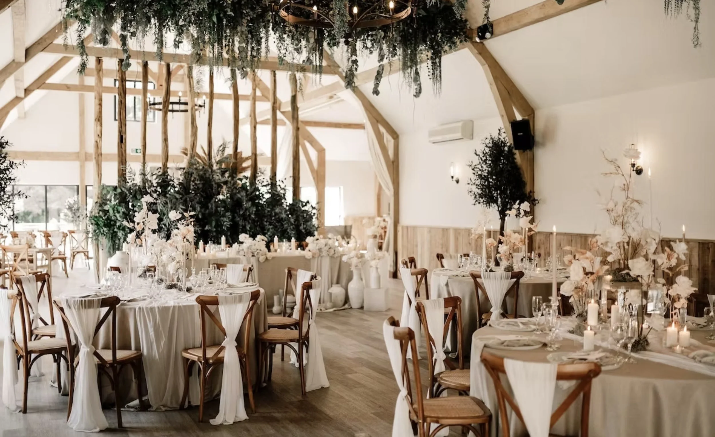 The River Barn, Poulton-le-Fylde, Lancashire — Wedding Reception Interior — Elegant wedding venue featuring exposed timber beams, vaulted ceilings, bespoke floral installations and beautifully arranged dining spaces within the renovated barn.