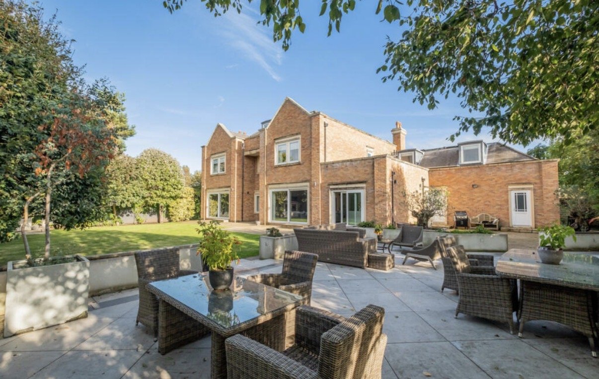 Regent Avenue, Lytham St Annes — Rear Garden and Terrace — landscaped rear garden of this substantial new-build family home, featuring an expansive stone-paved terrace, outdoor dining and seating areas, and traditional red-brick elevations. The desig