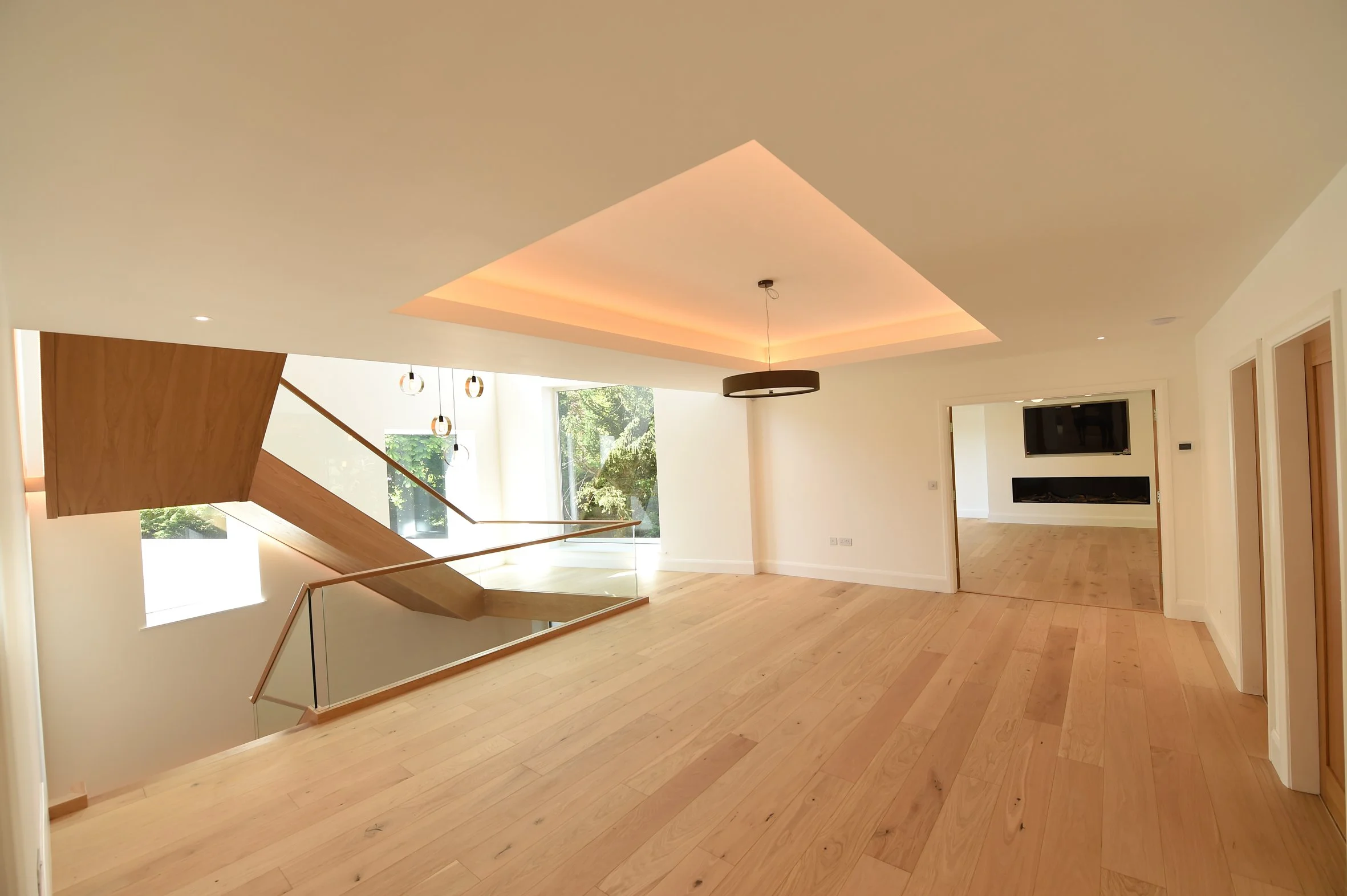 8 Church Drive, Lytham – First Floor Landing

Architectural photograph of the spacious first-floor landing, featuring natural oak flooring, a sculptural timber staircase, glass balustrades and a recessed ceiling with concealed LED lighting.