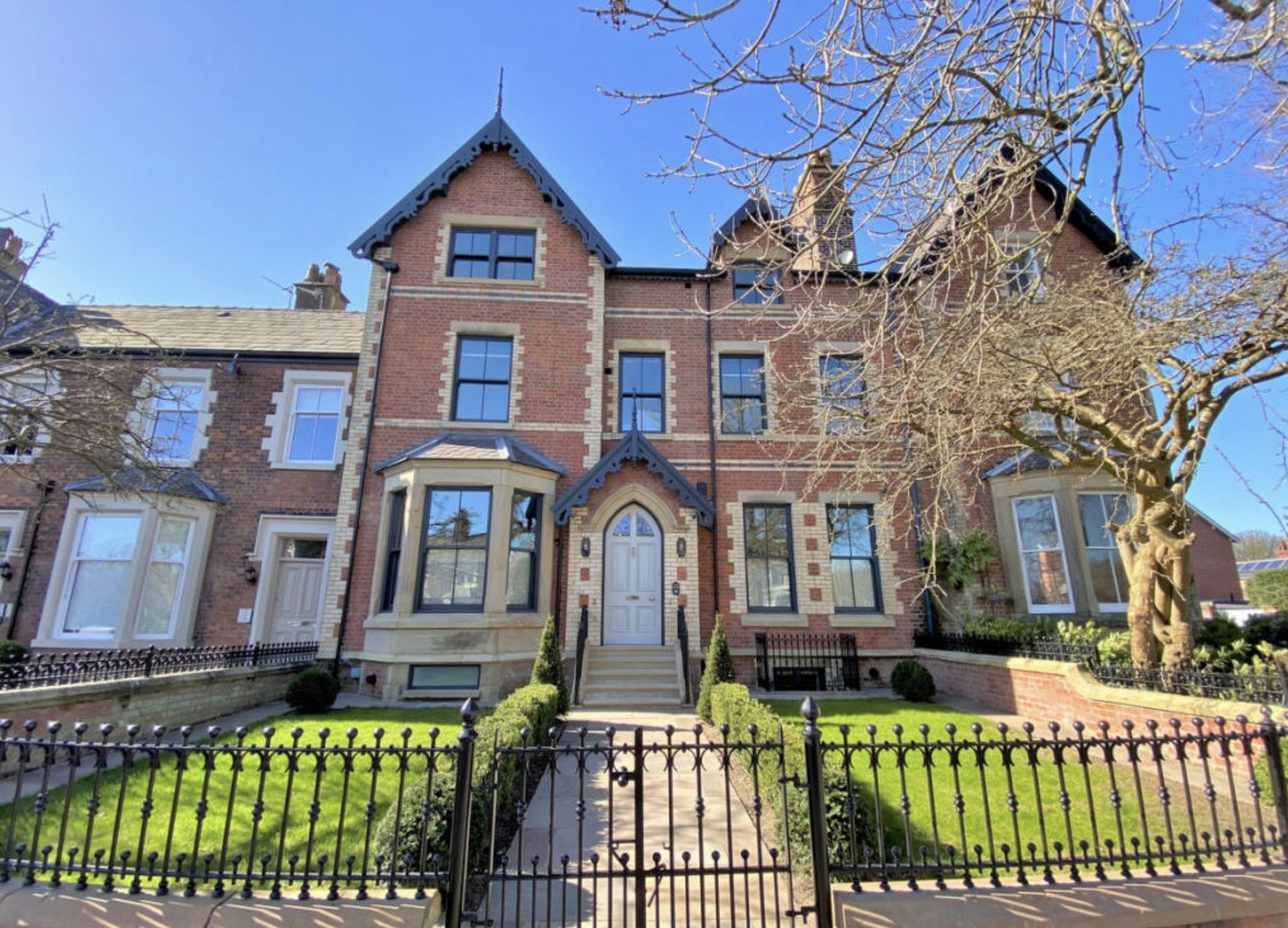 Restored Victorian façade with traditional entrance gates and landscaped frontage.