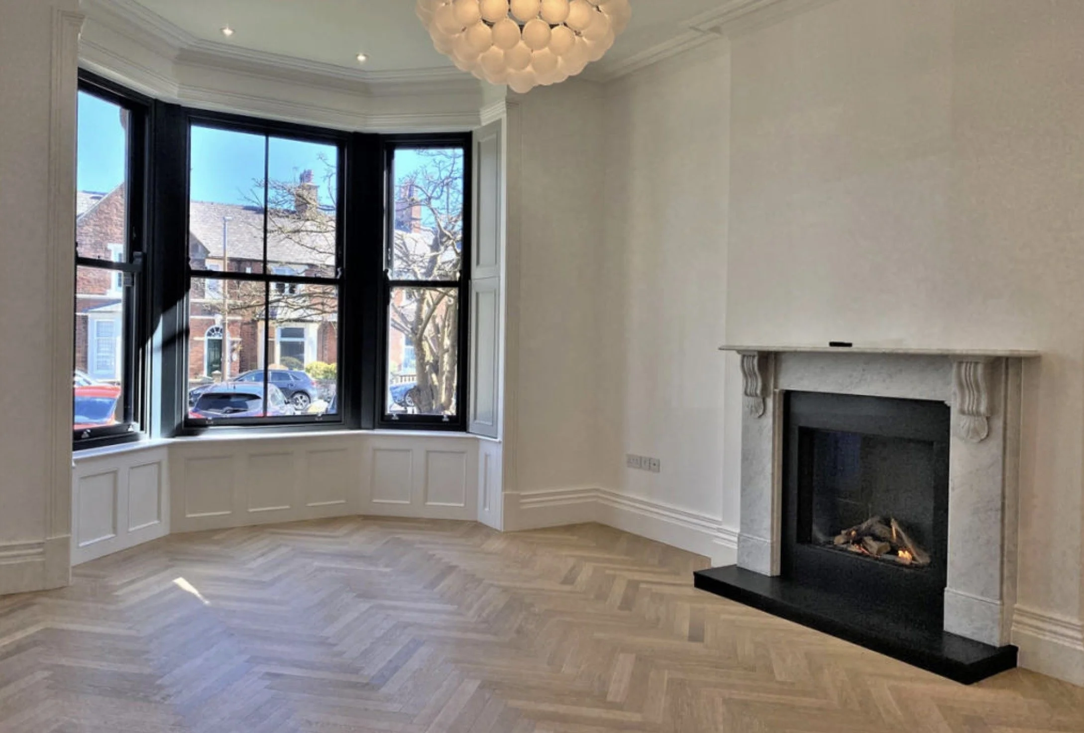 Bright bay-windowed living room with new fireplace and period proportions.
