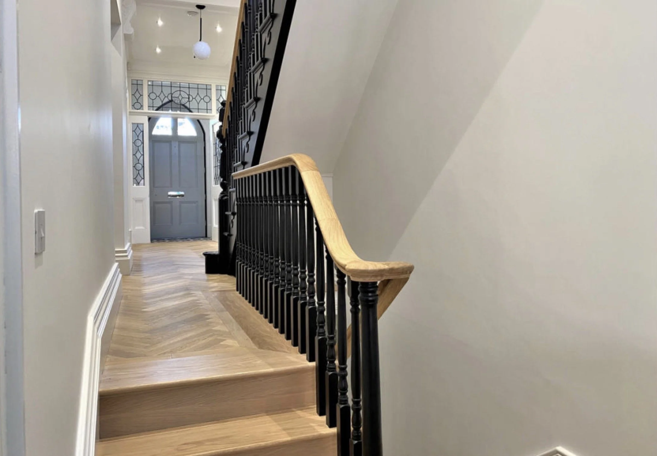 New staircase with sweeping timber handrail and decorative tiled landing.