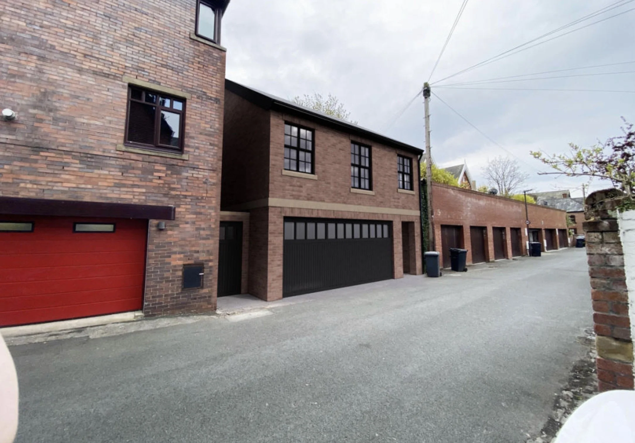 Rear garage annexe with brick elevations, first-floor accommodation, integrated garages and paved access courtyard.