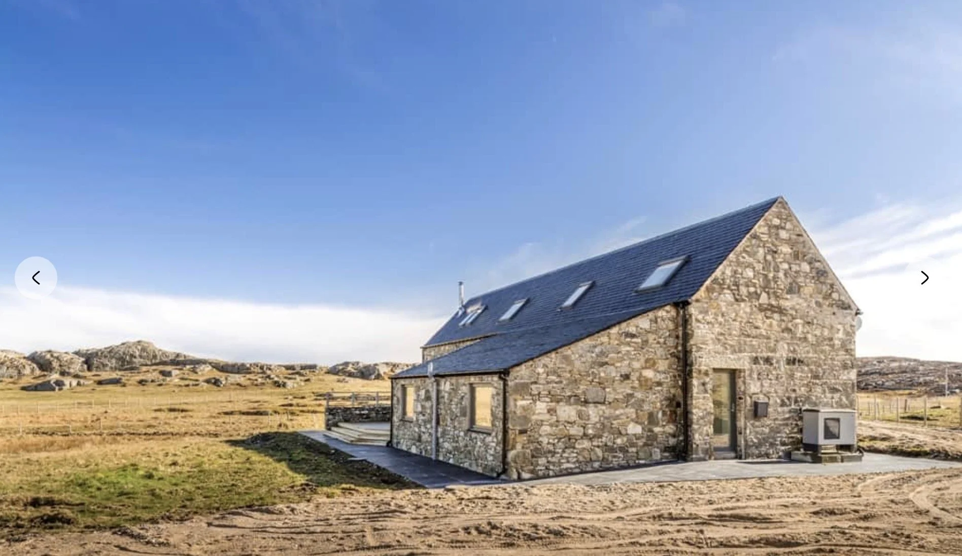 Traditional stone architecture surrounded by open moorland and distant sea views.
