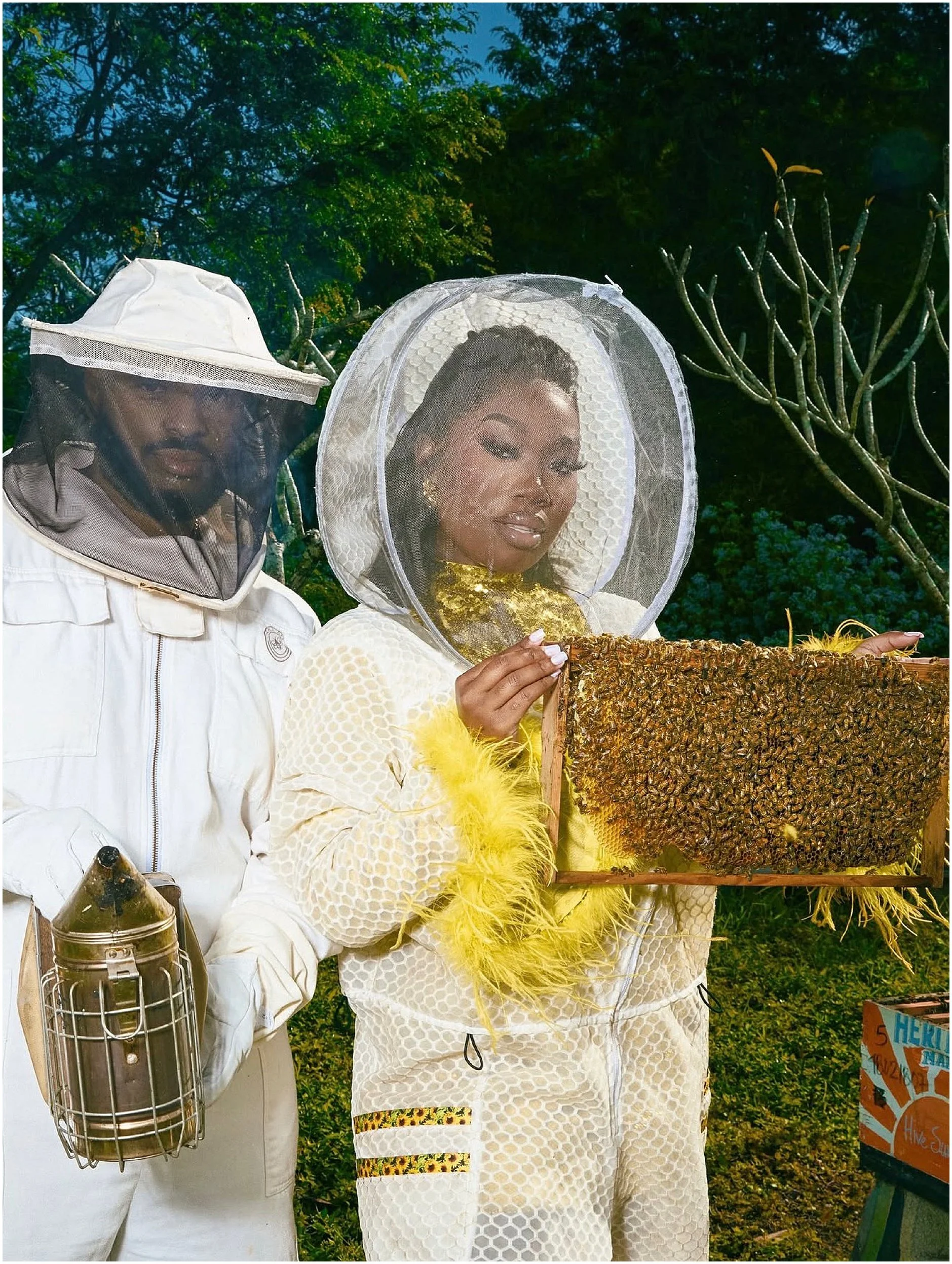 Engagement portrait of Erika and her fiancé in a beekeeping setting featuring the Jeometry Sunny Suit protective gear for women.