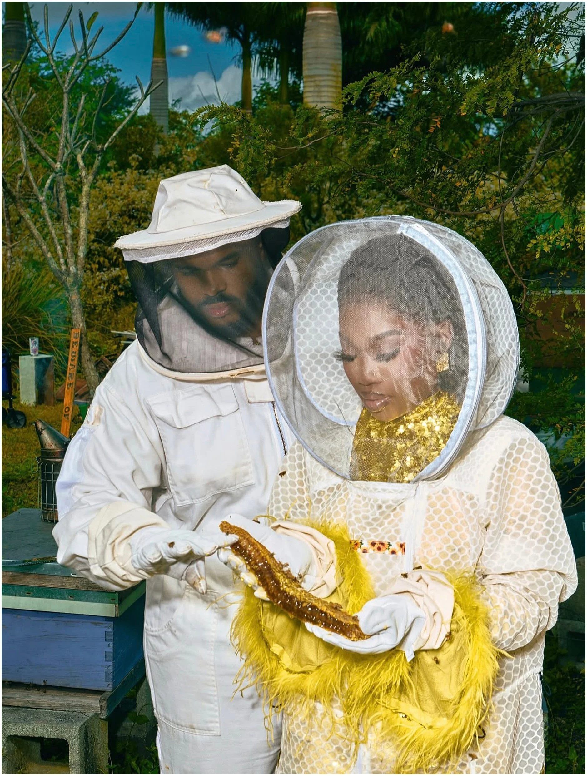 Close-up of Erika in the Jeometry Sunny Suit veil smiling among honeybee hives during her engagement photos.