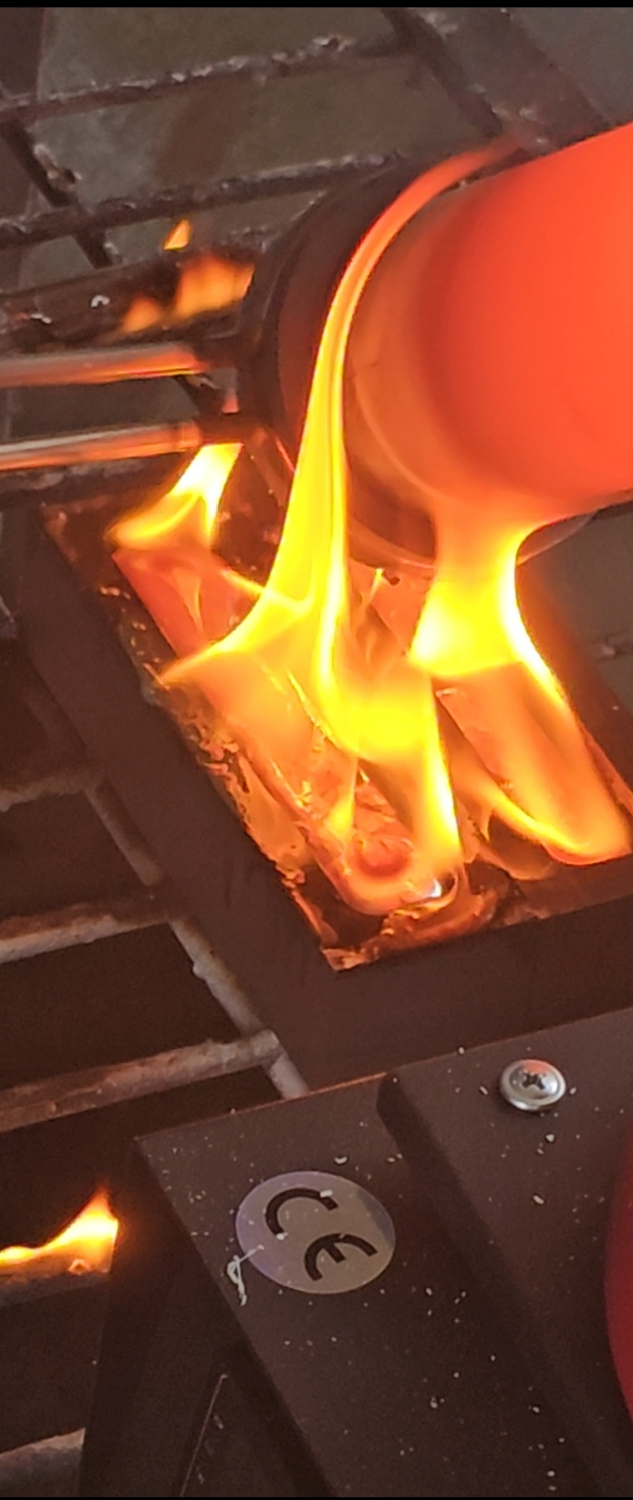 A gas stove burner with orange flames coming from the metal ring around the flame.