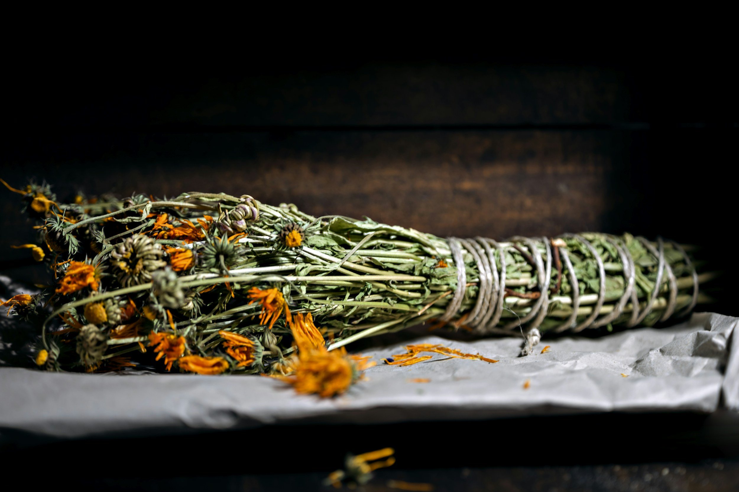 Dried flower bouquet bound with string, resting on crumpled paper