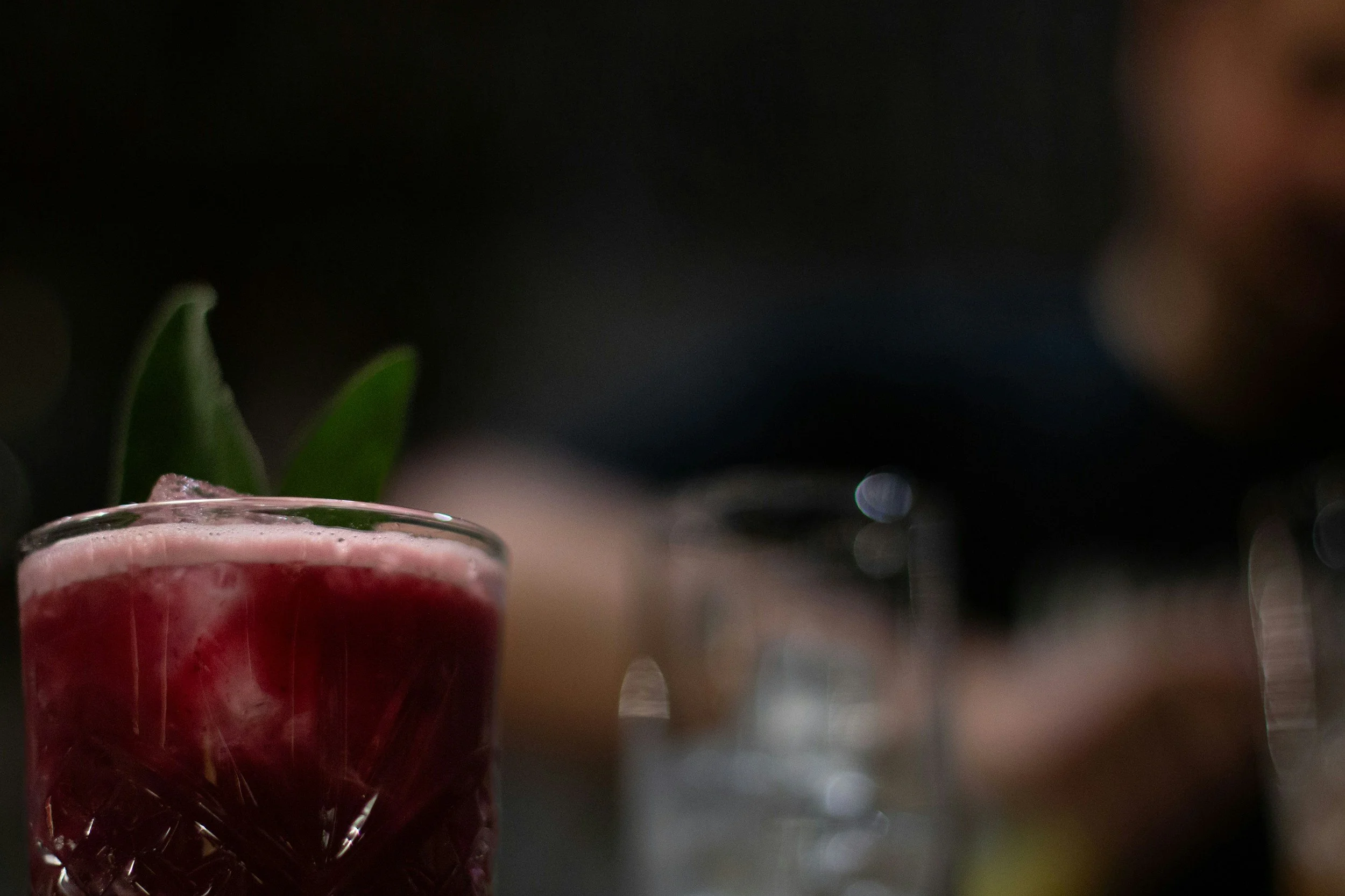 Red cocktail in a glass tumbler at a bar photographed at a low angle