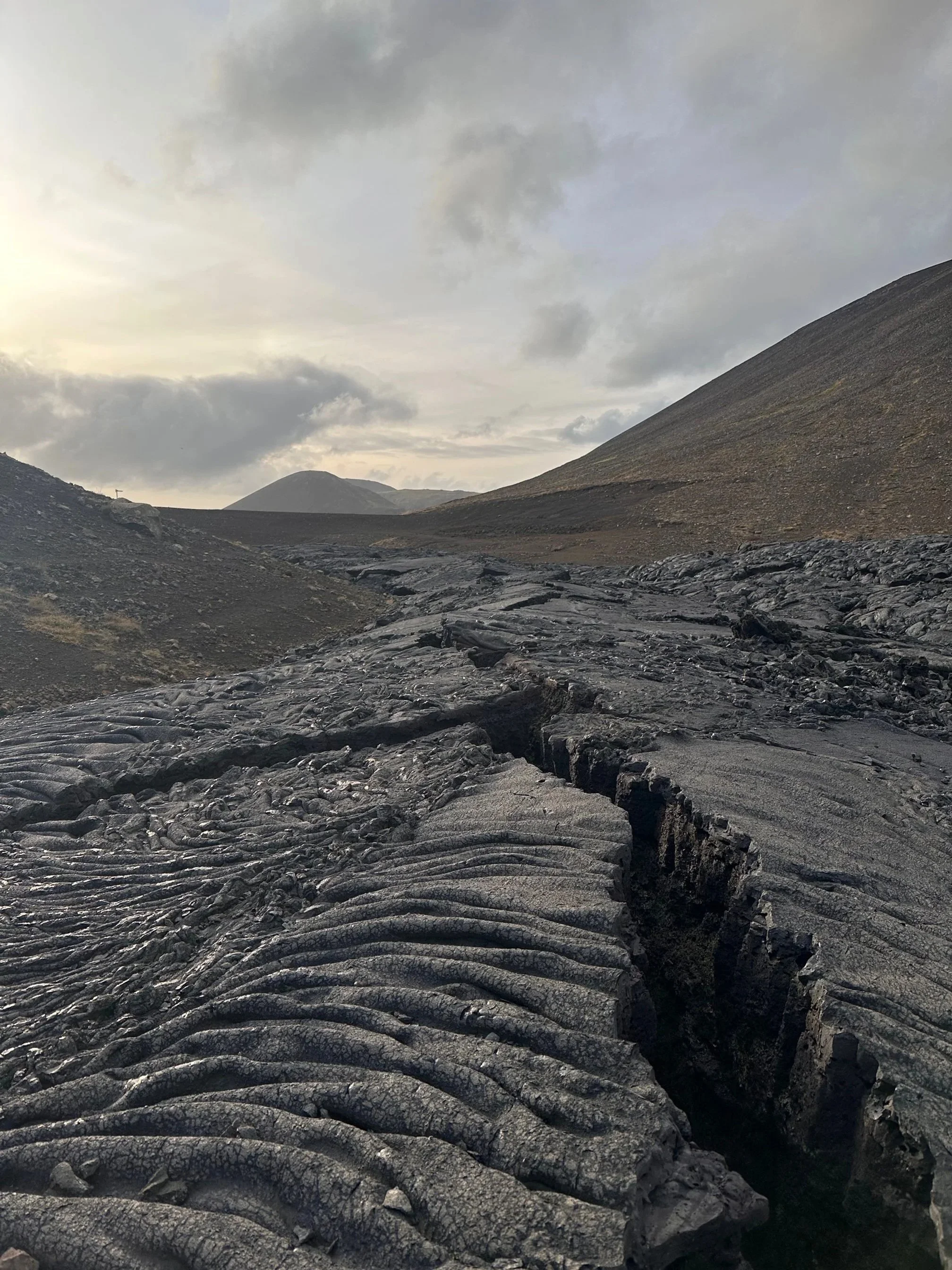 Icelandic solidified lava fields. Lava rock fissure with volcanic hills on the horizon.