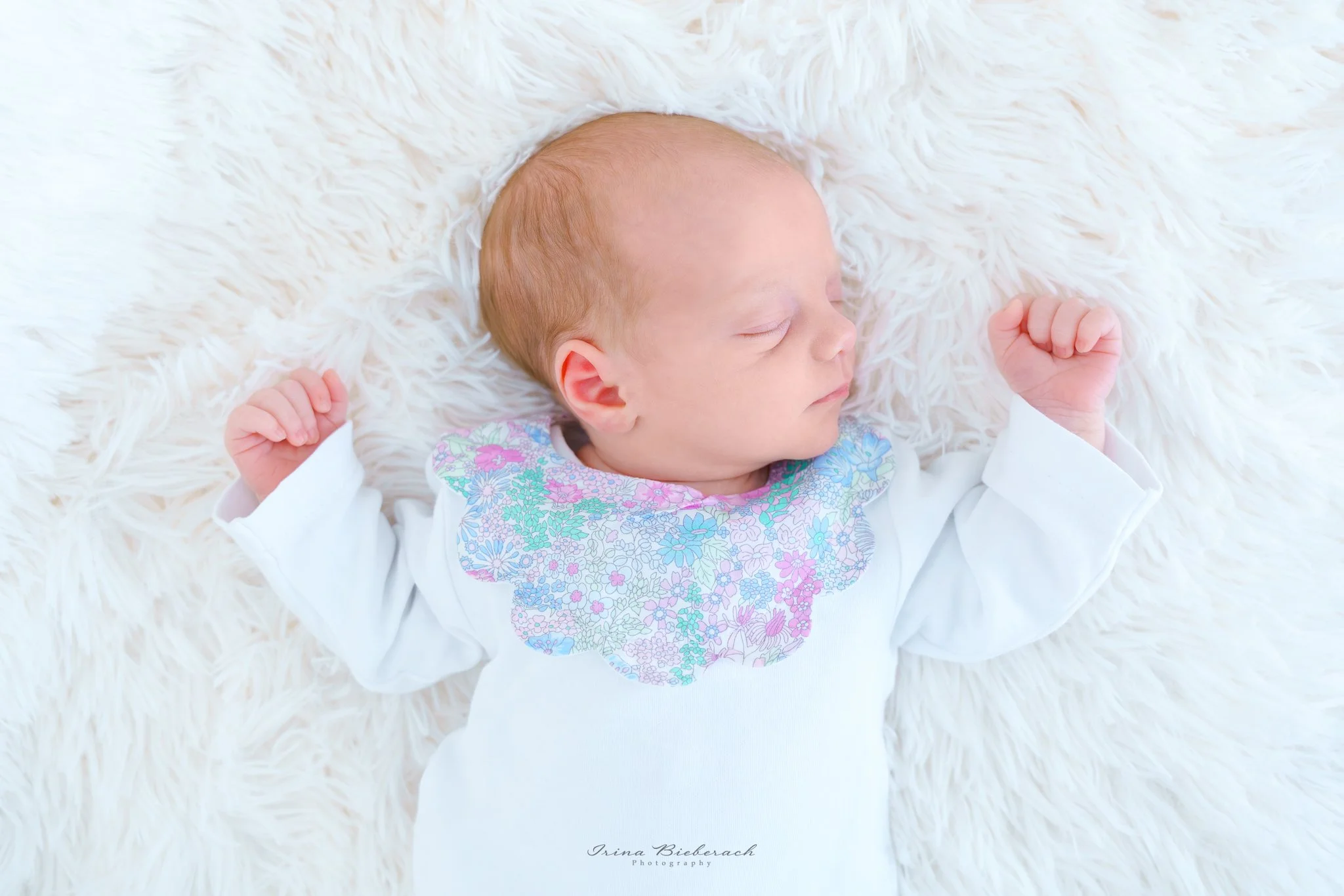 Nouveau-né habillée en body blanc dors paisiblement  sur une couverture douce blanche