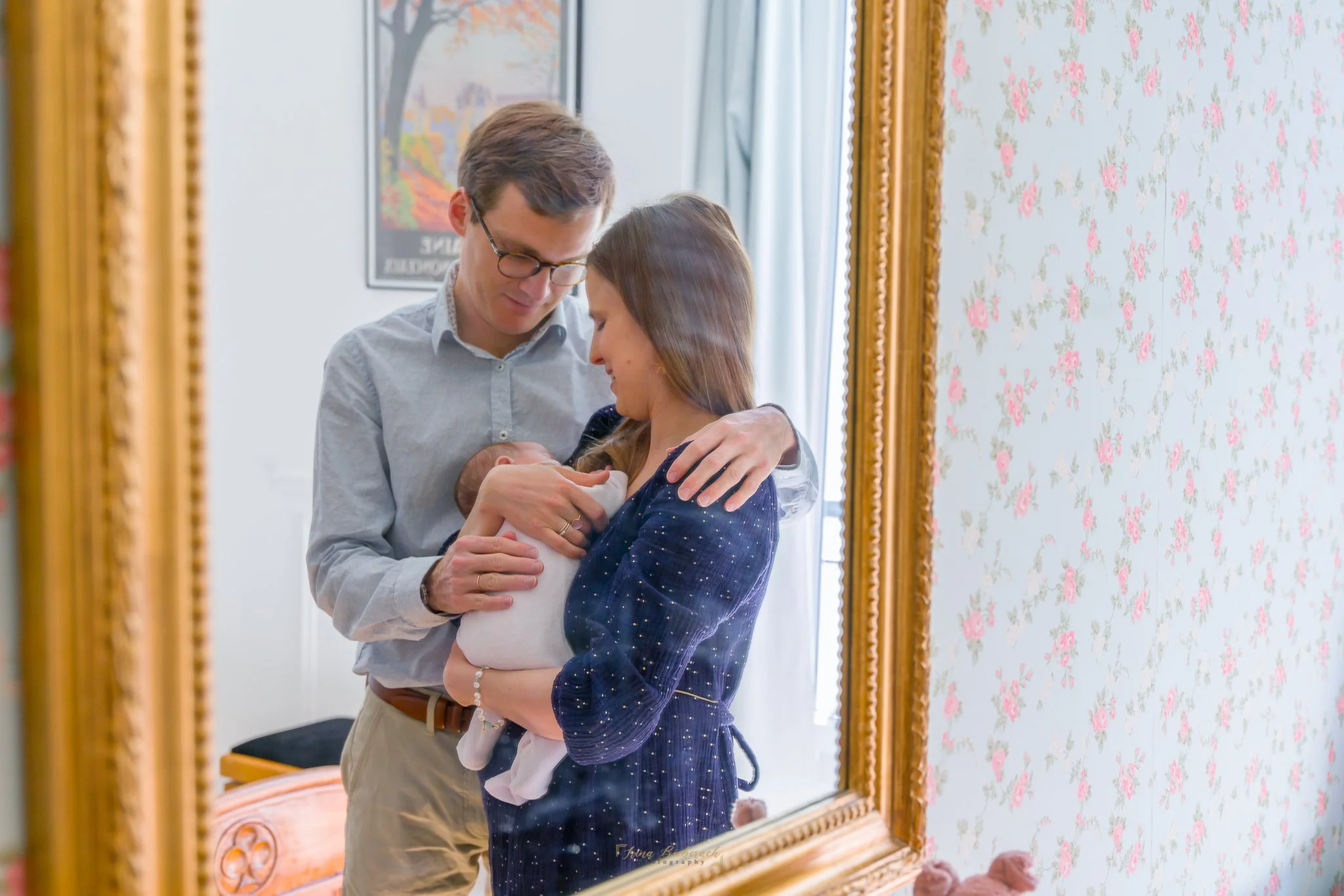 Reflet dans un miroir d'un jeune couple de nouveaux parents en regardant leur bébé dormir dans les bras de sa mère 