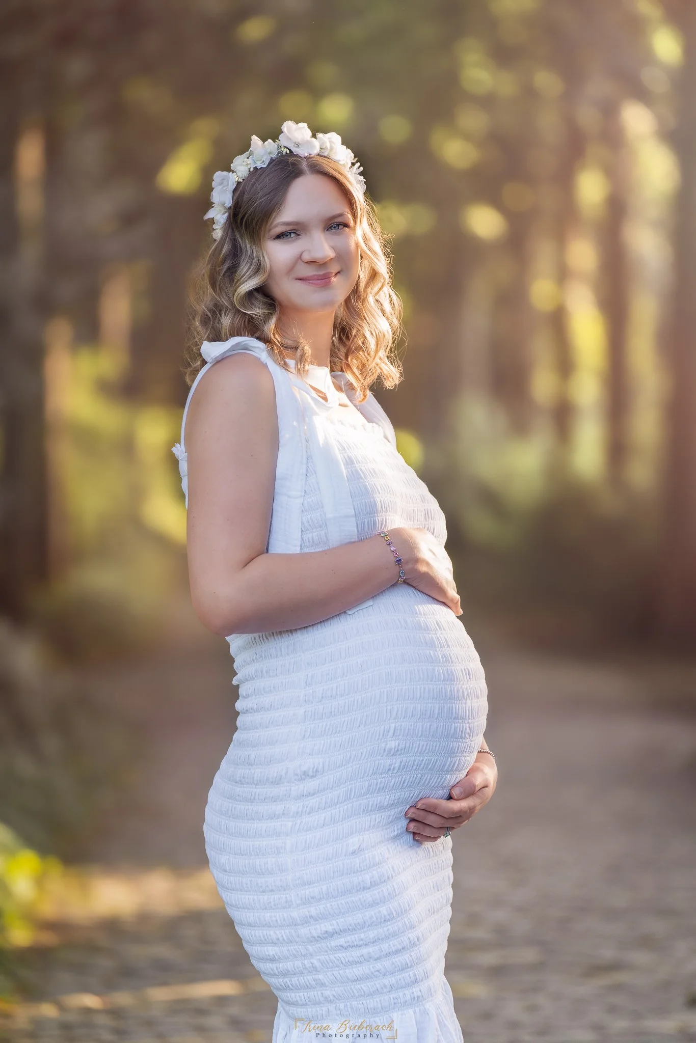 Femme  enceinte pose doucement en contre jour  pendant un coucher de soleil dans le parc de l île Saint Germain