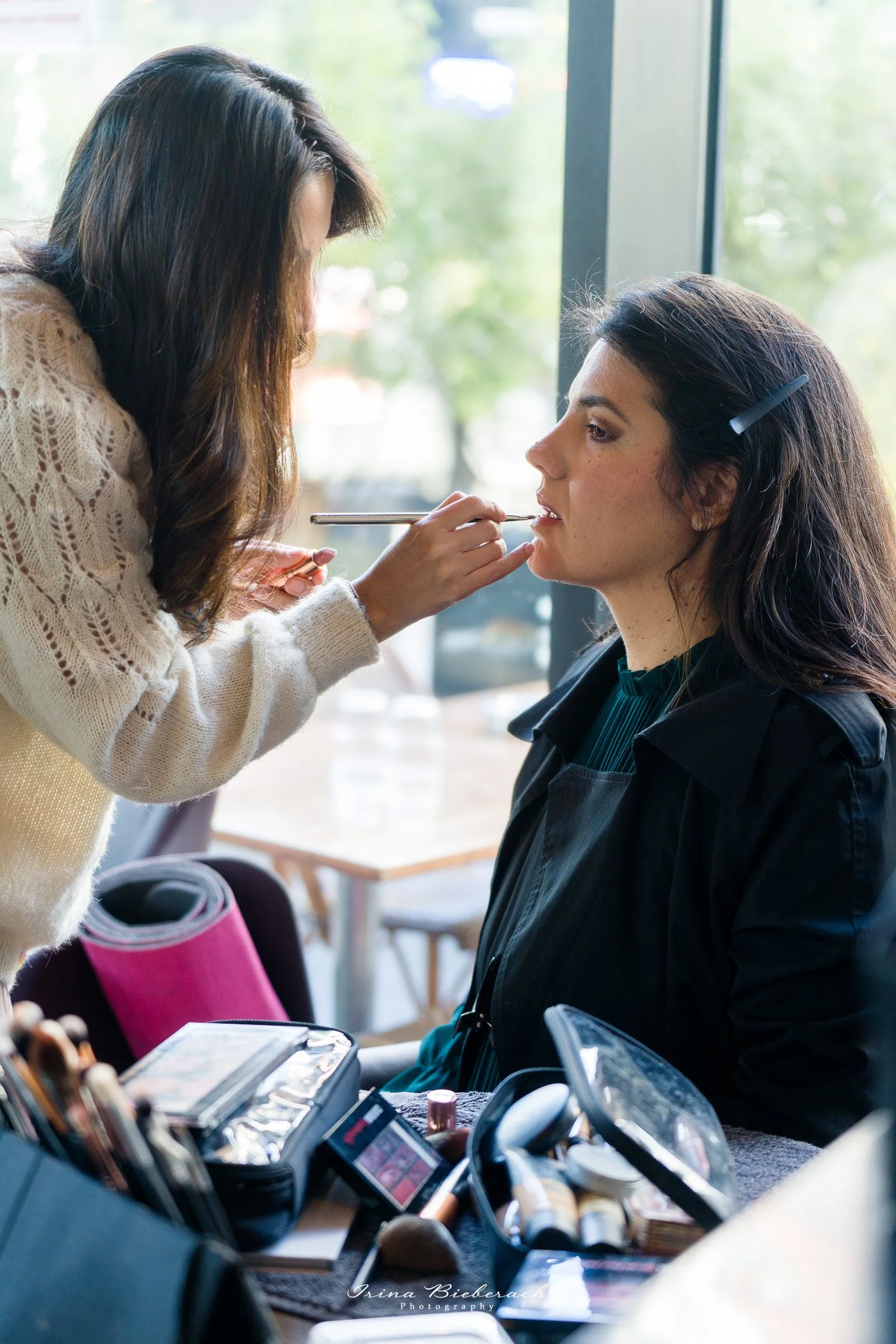 Maquilleuse professionnelle applique maquillage sur jeune femme lors de préparatifs pour une prise de vues