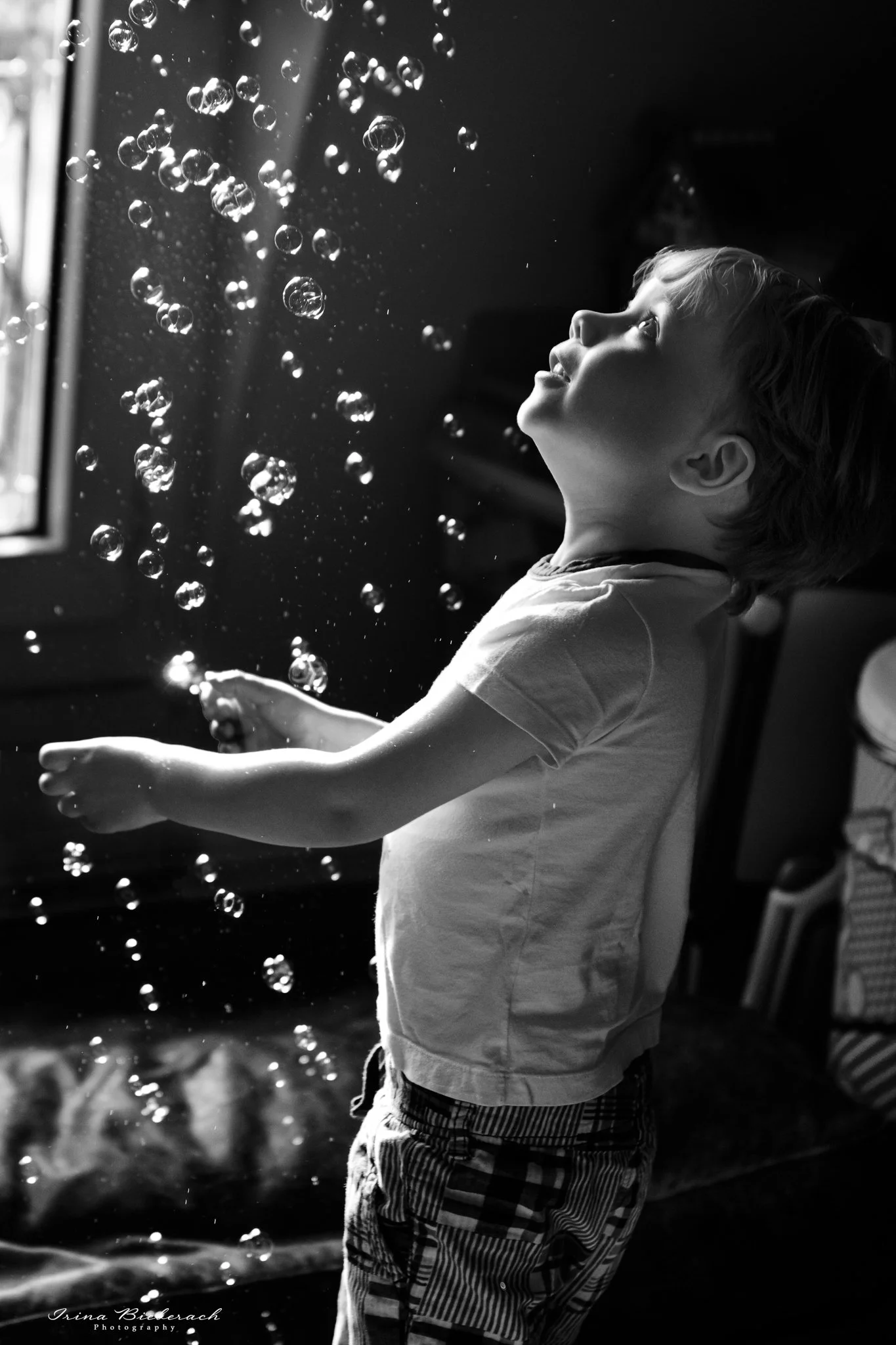 Petit garçon joue avec des bulles de savon dans une chambre d’appartement parisient
