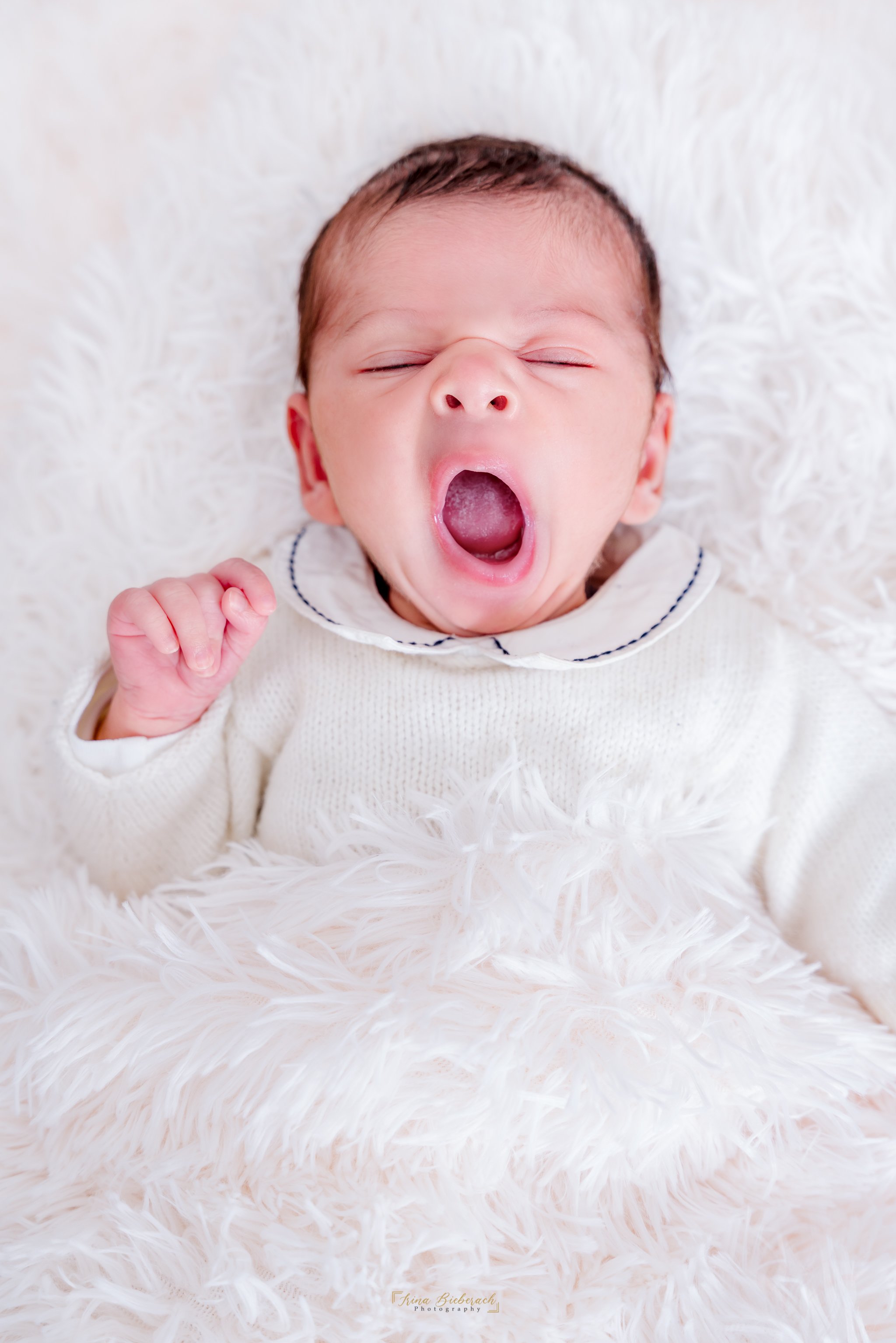 Nouveau ne baille allongé sur une couverture douce blanche