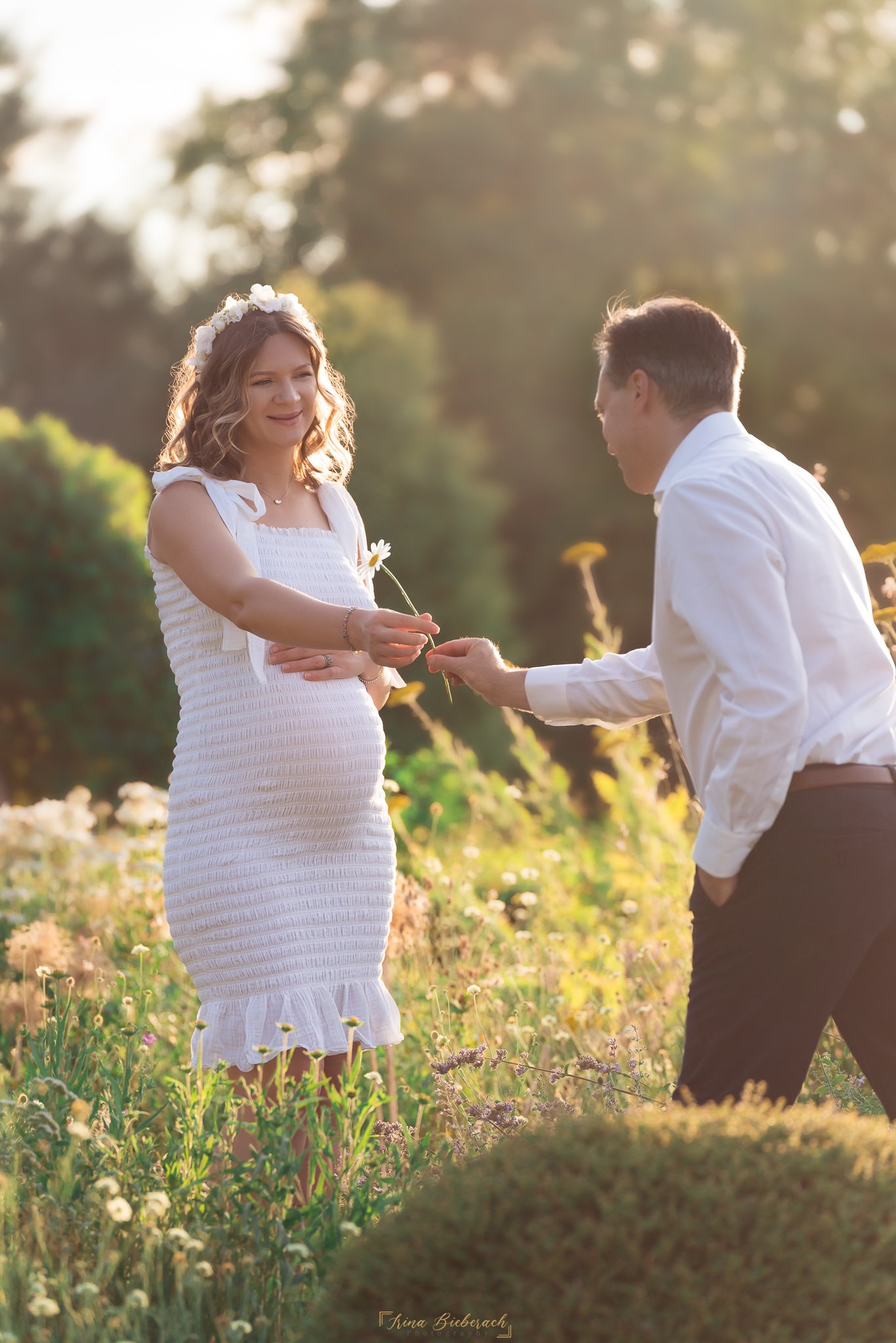 Uh homme donne une fleur à sa femme enceinte pendant le coucher du soleil d’été dans le parc de l'Ile Saint Germain