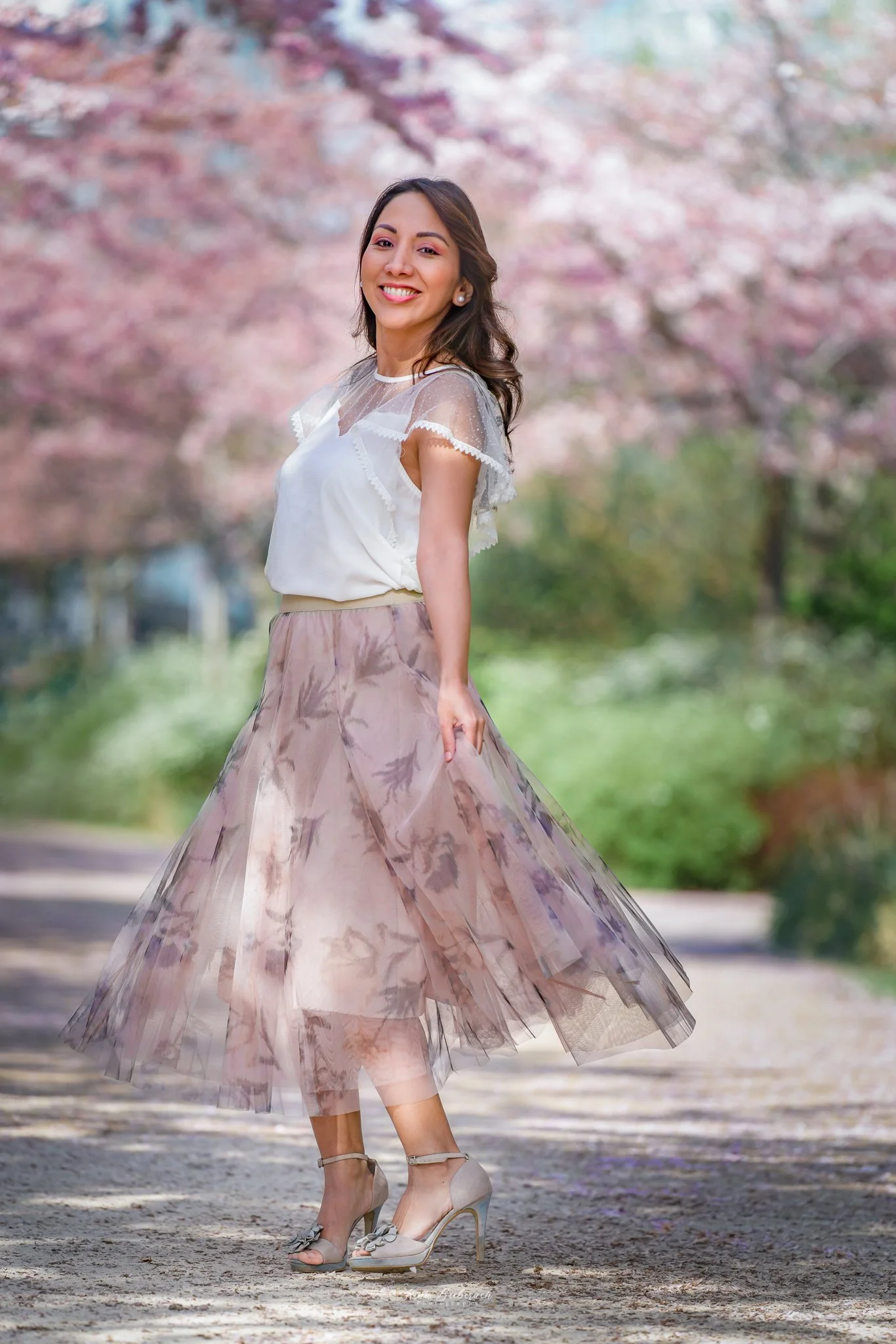 Jeune femme danse dans une allée fleurie de cerisiers japonais roses dans le Parc de Billancourt