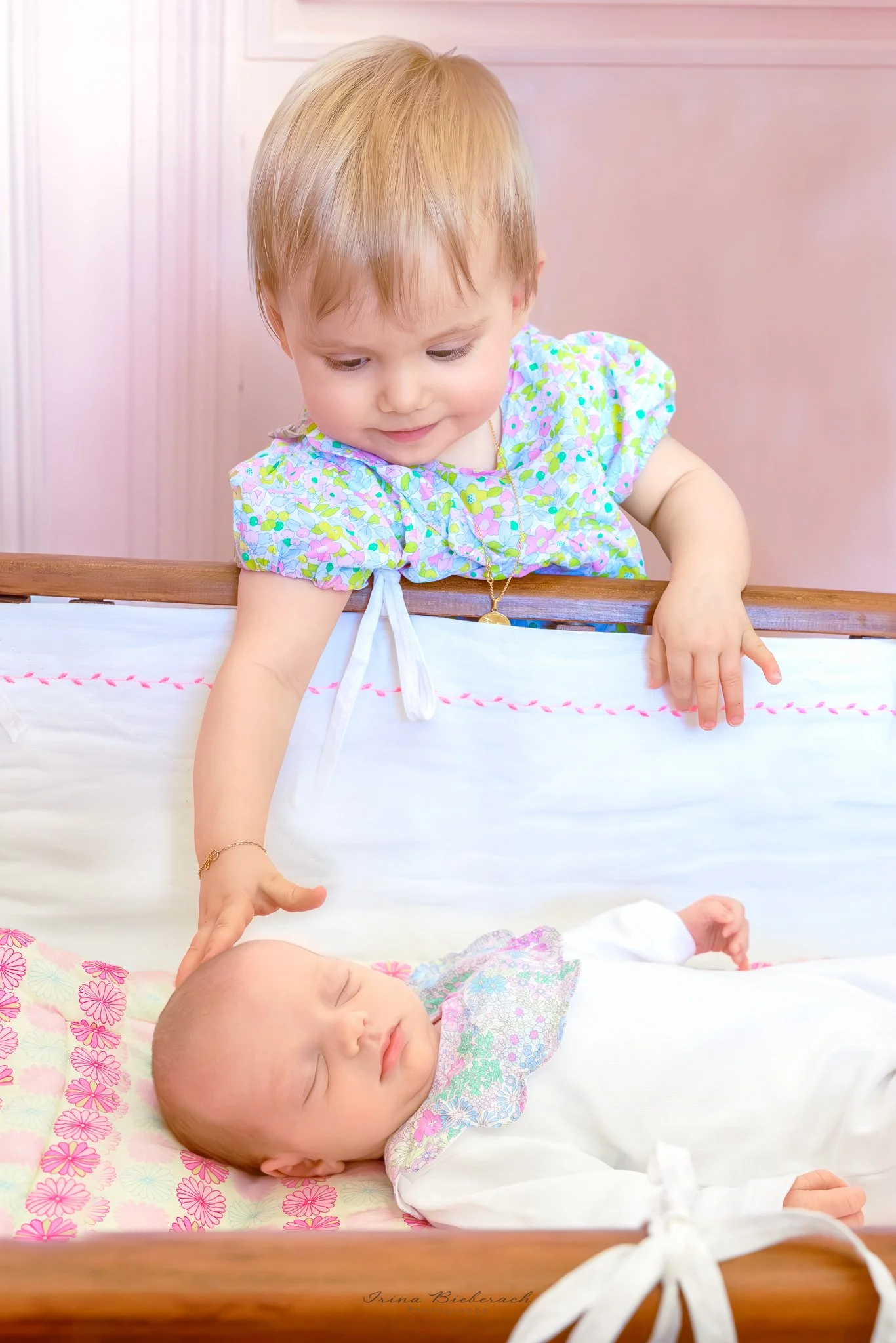 Petite fille touche la tête de sa sœur bébé qui dort dans son lit en bois de bébé 