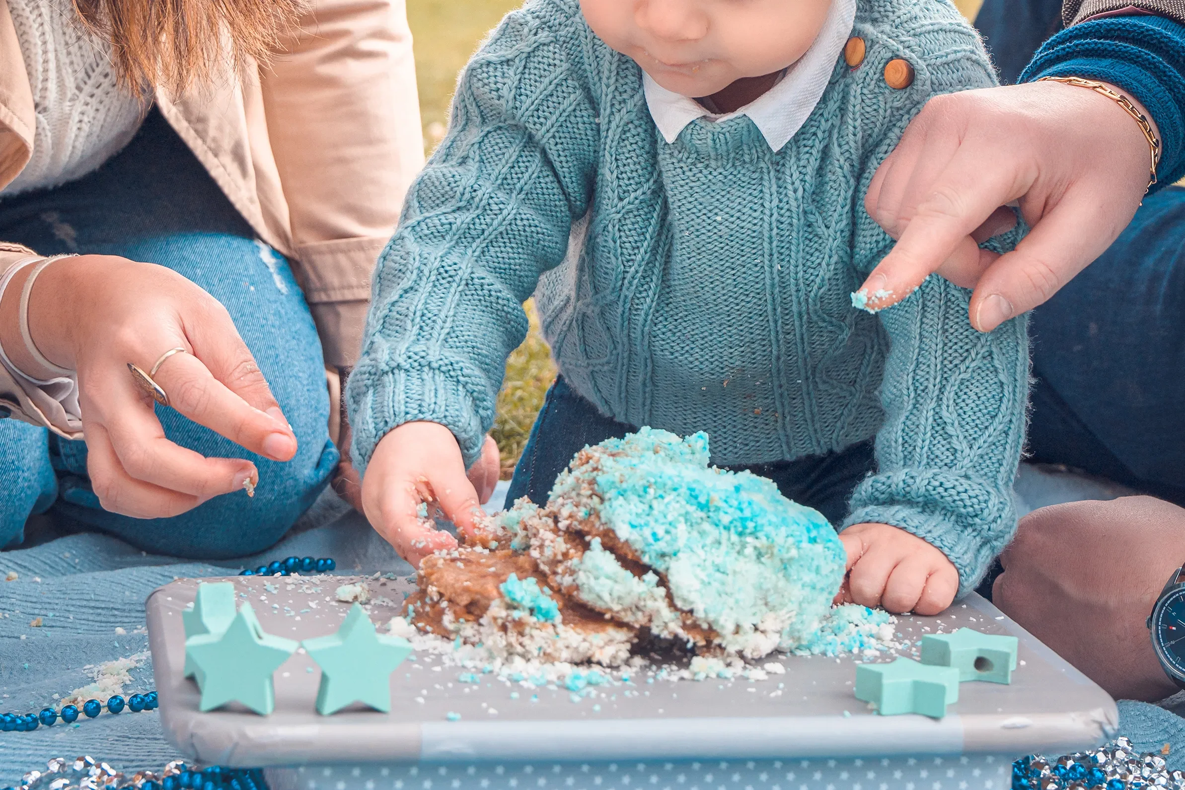 Famille mange un gâteau d'anniversaire bleu lors d'une séance photo d'anniversaire d'un an en extérieur à Paris