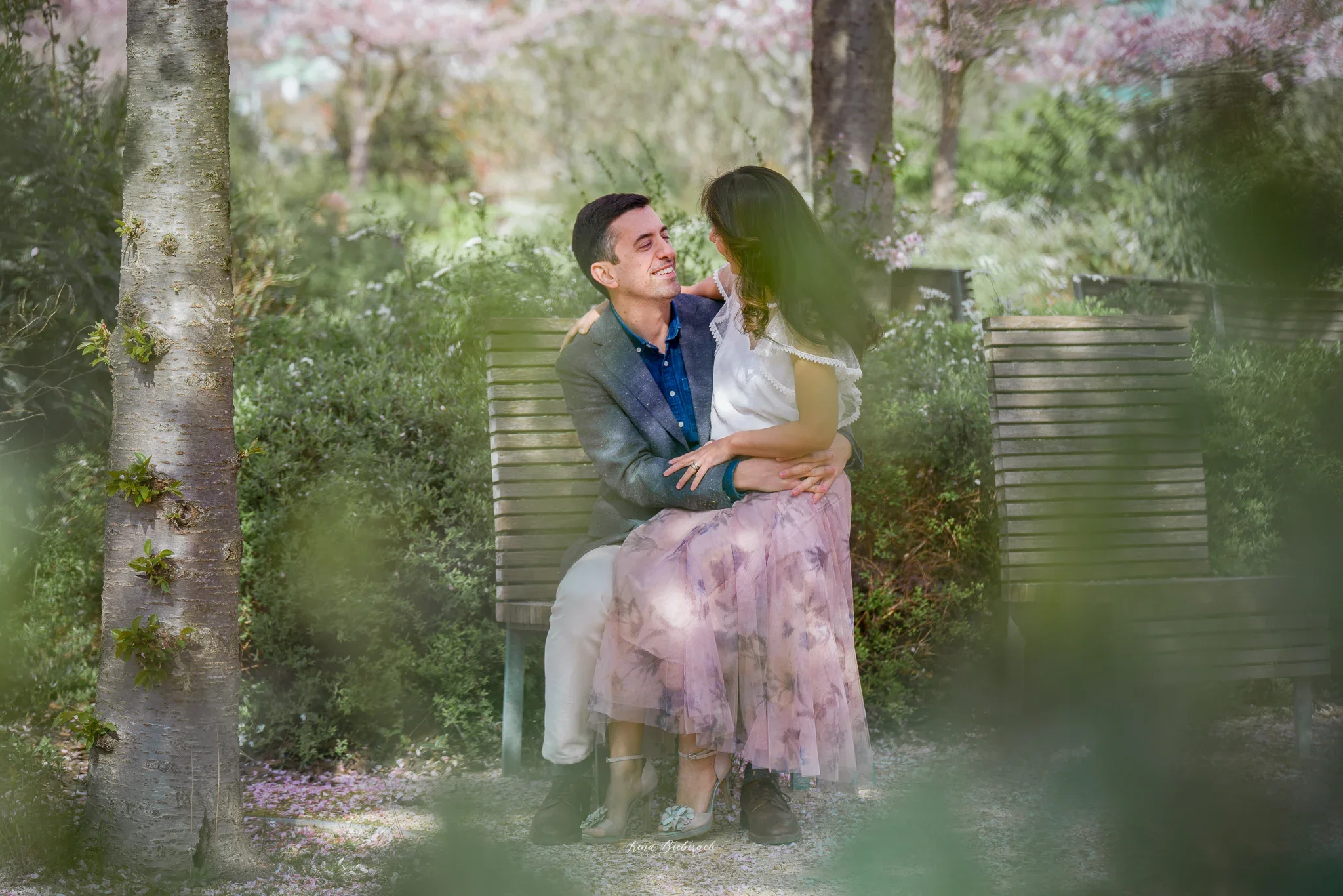 Shooting photo d'un couple marié assis entre les cerisiers japonais dans un parc près de Paris