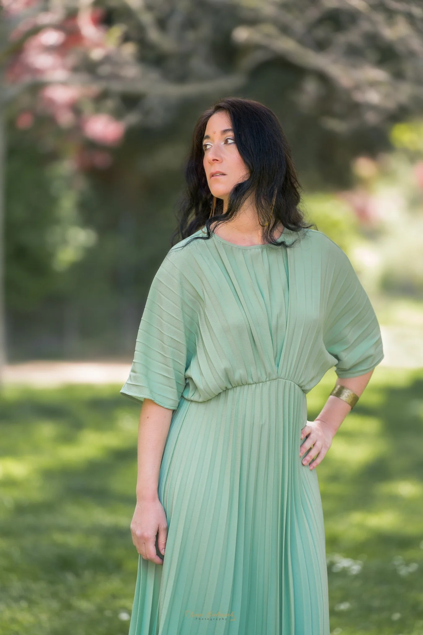 Femme habillée en vert pose dans un jardin parisien sous la lumière naturelle