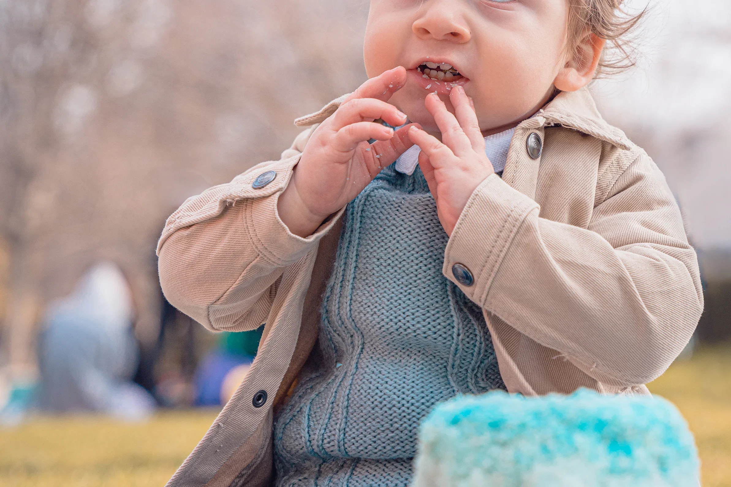 Gros plan d'un bébé qui porte sa main à la bouche pour goûter son premier gâteau d'anniversaire.