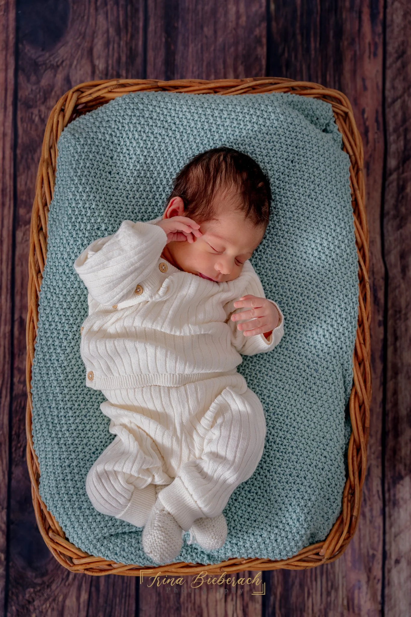 Garçon nouveau-né dort sur une couverture tricotée  turquoise pastel dans un panier en osier