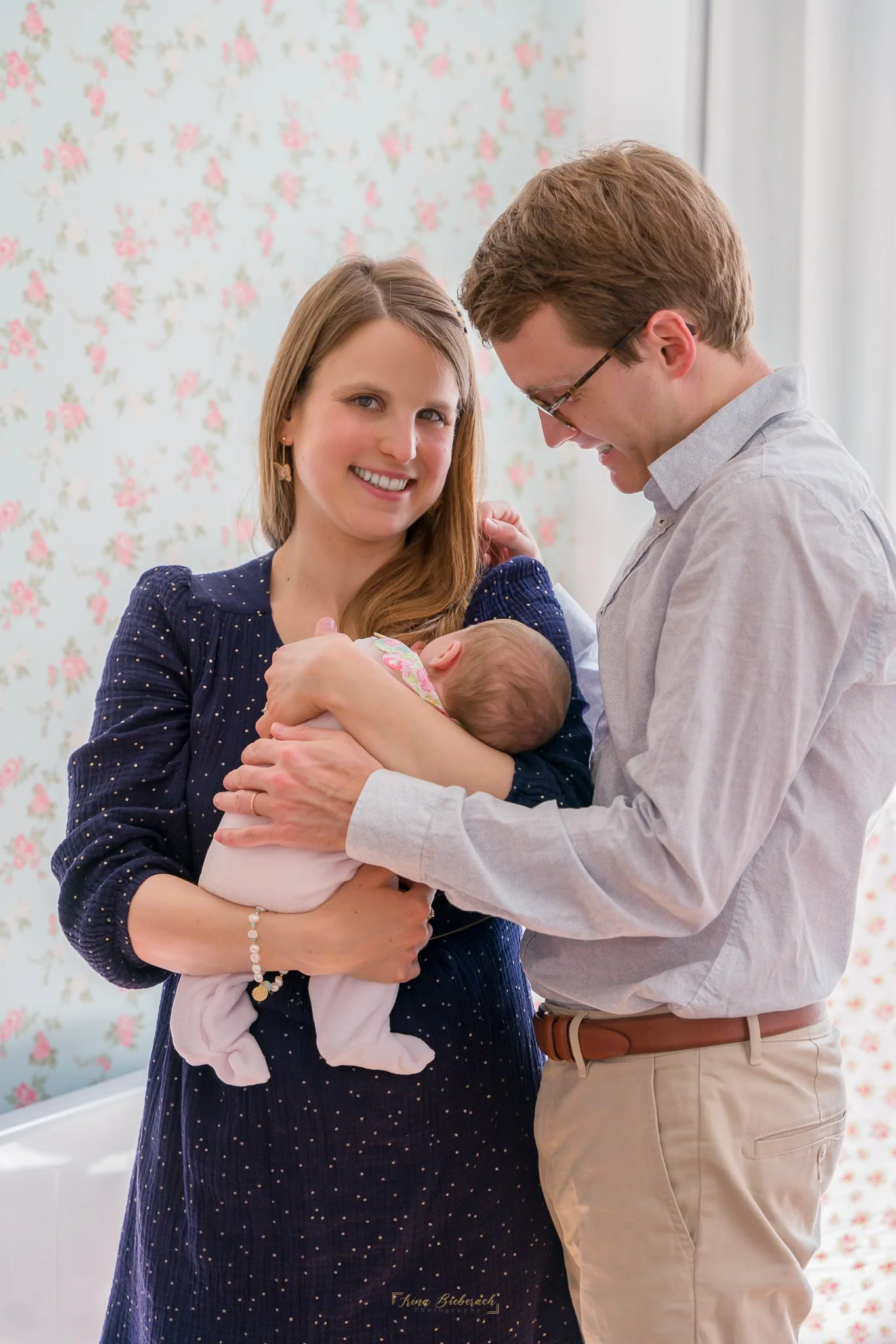 Parents regardent leur bébé dans une chambre illuminée par lumière naturelle