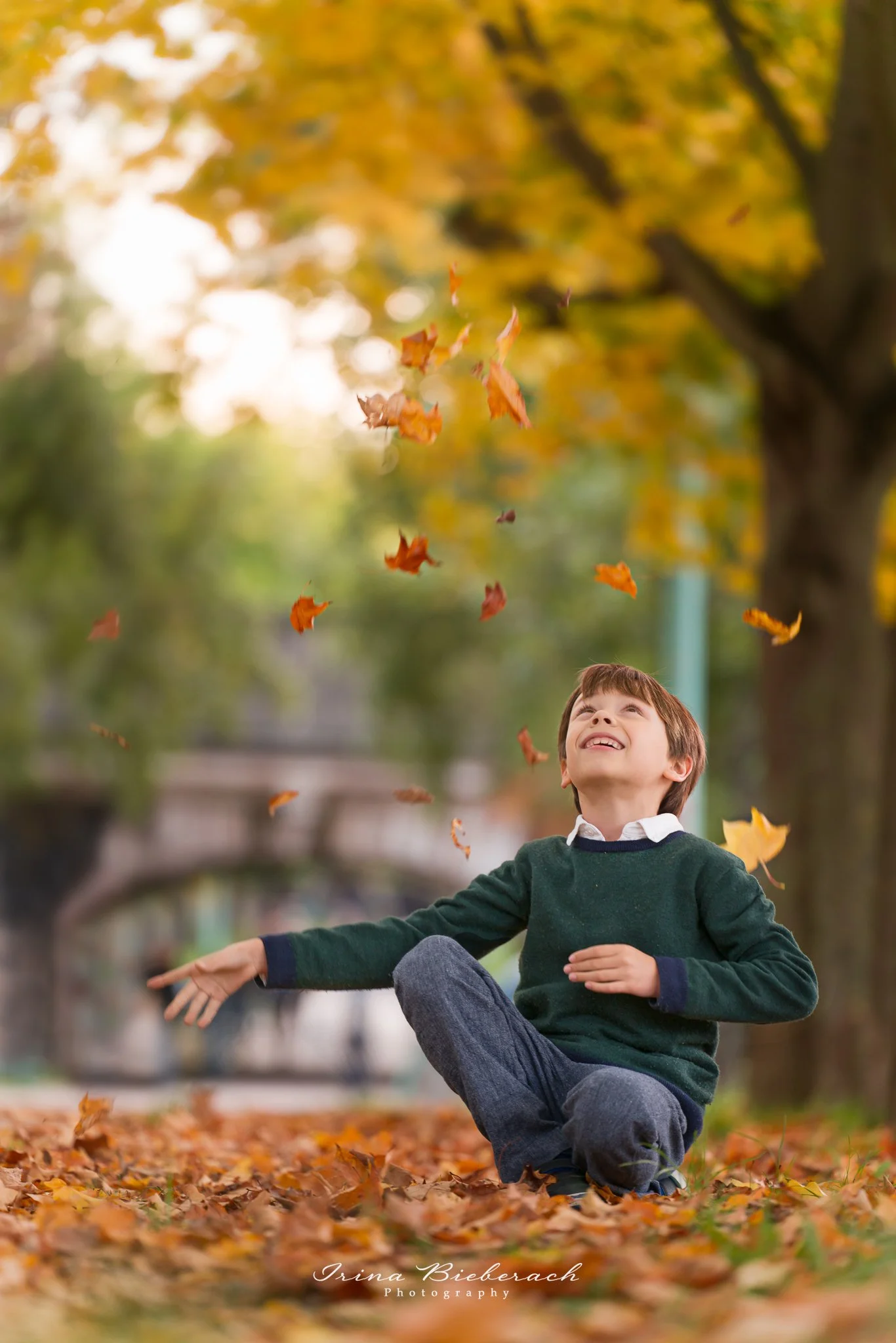 Enfant jouant avec des feuilles mortes dans un parc à Paris