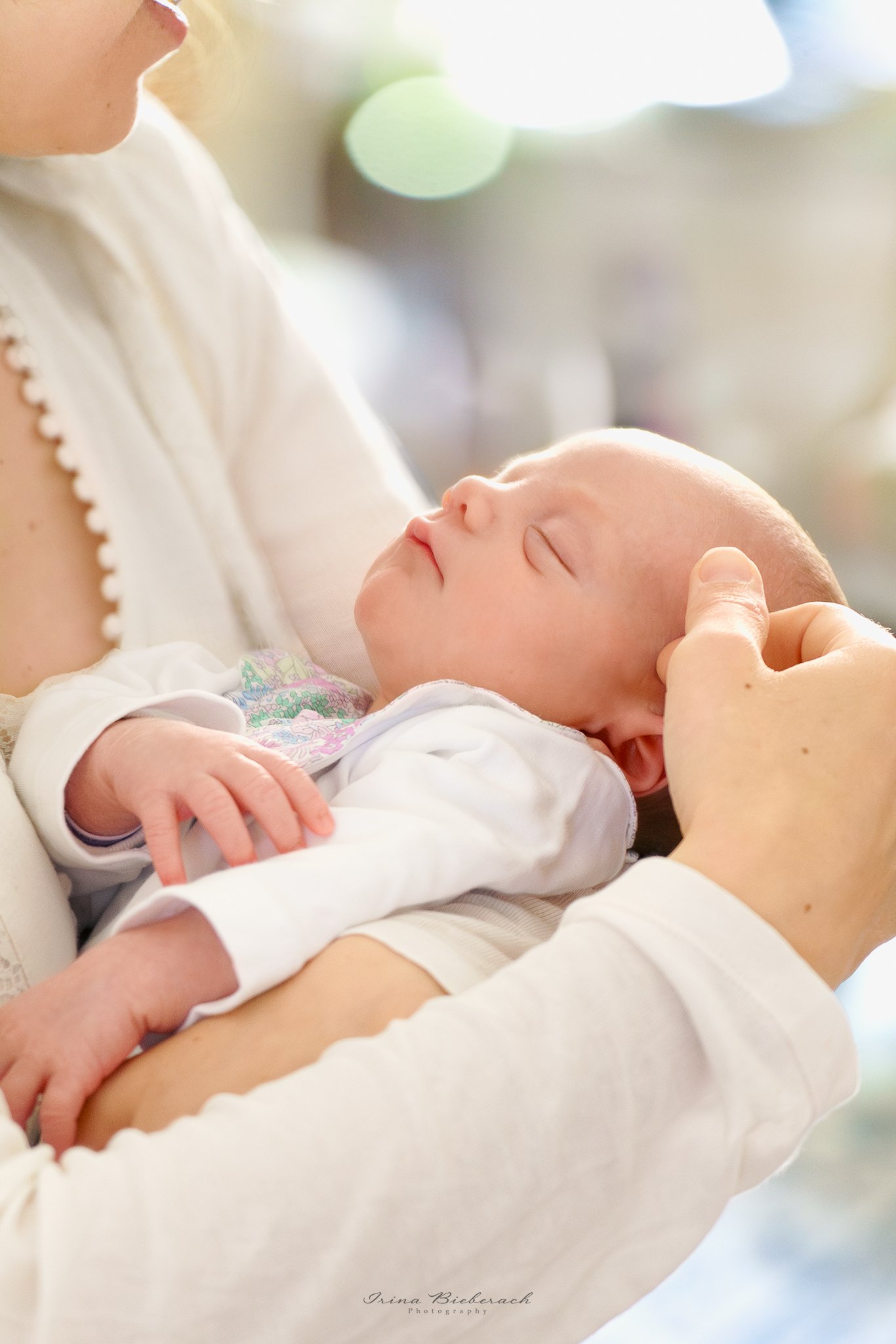 Bébé fille dort dans le bras d'une femme qui caresse sa tête tendrement 