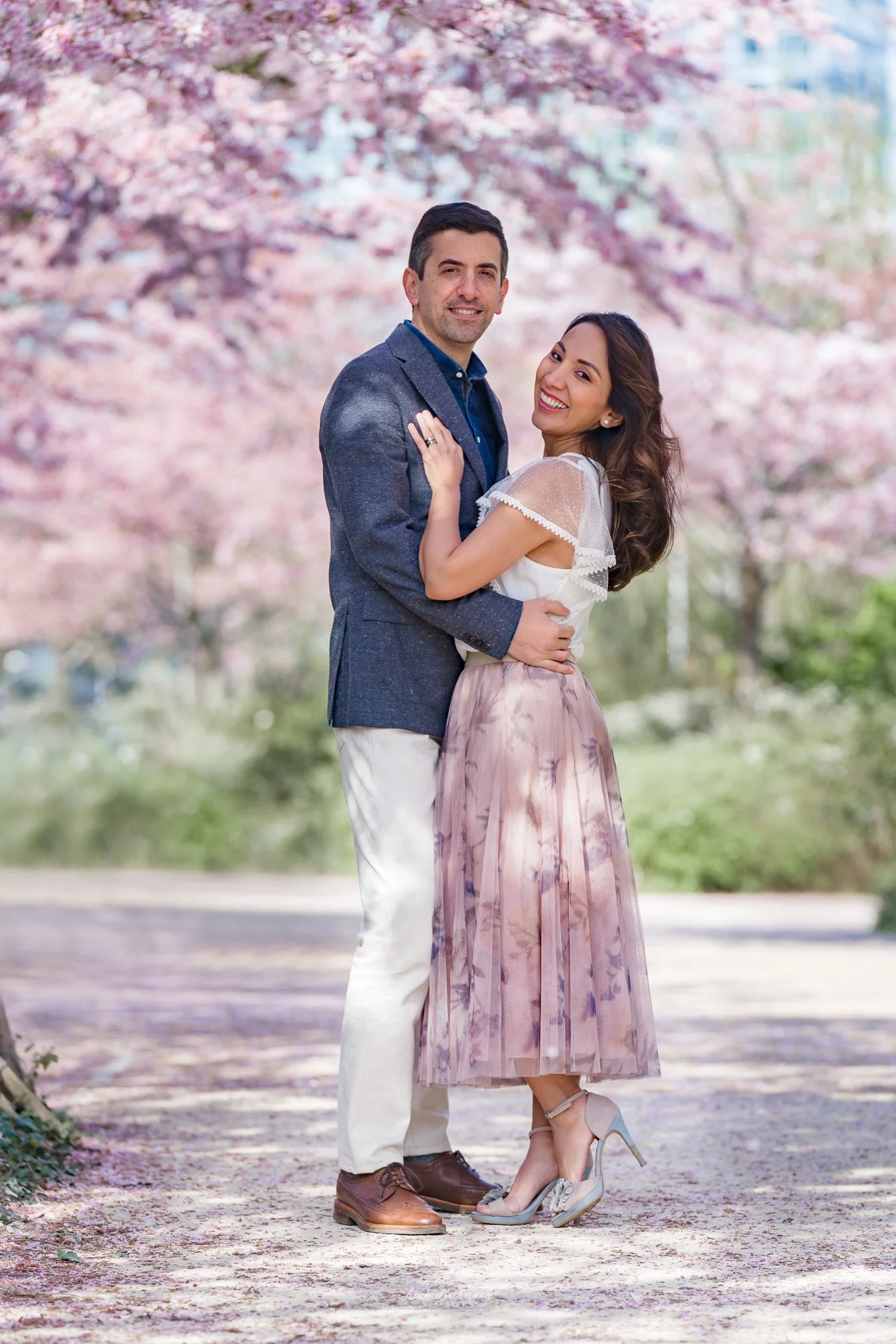 Couple souriant pose sous les cerisiers japonais en fleurs à Paris