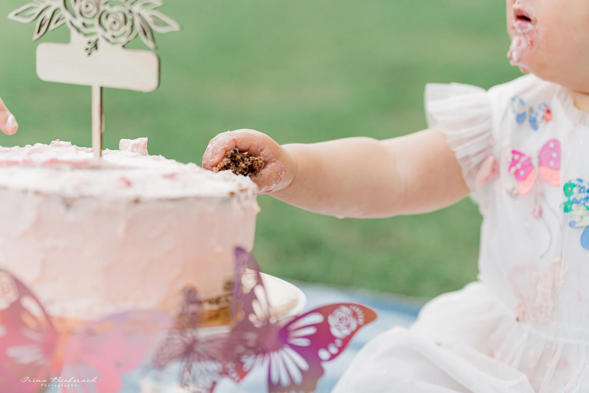 Main d'enfant touchant un gâteau au chocolat décoré en rose pour anniversaire de bébé