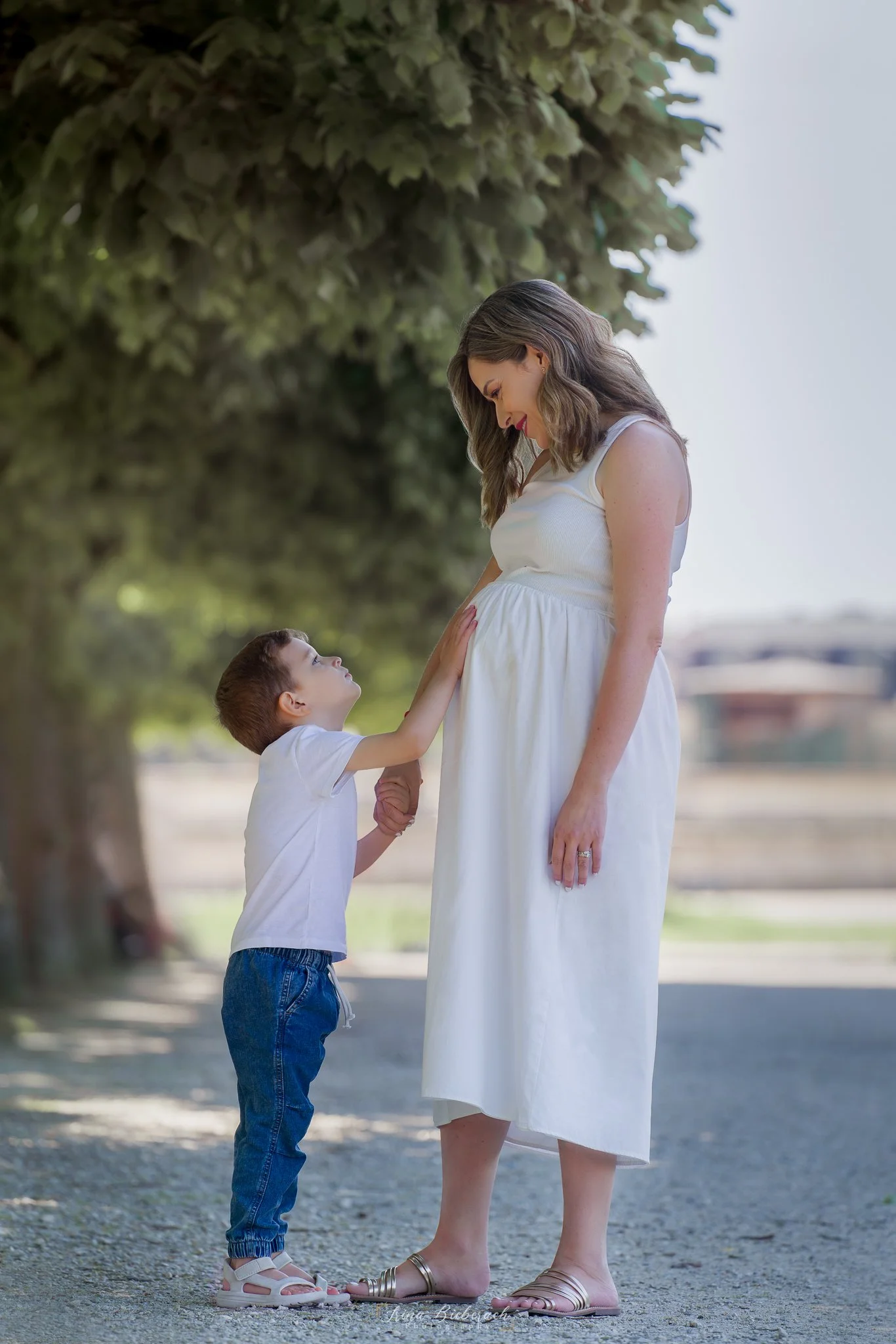 Femme enceinte regarde son enfant qui touche son ventre rond dans les jardins du château de Saint Germain en Laye