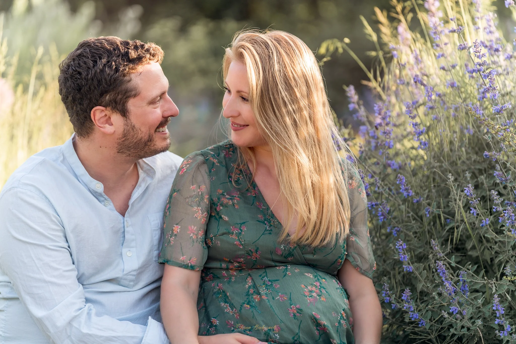 Couple d’amoureux assis entres les fleurs se regardant , dans le  parc de l’ile Saint Germain au couché du soleil pendant l’été 