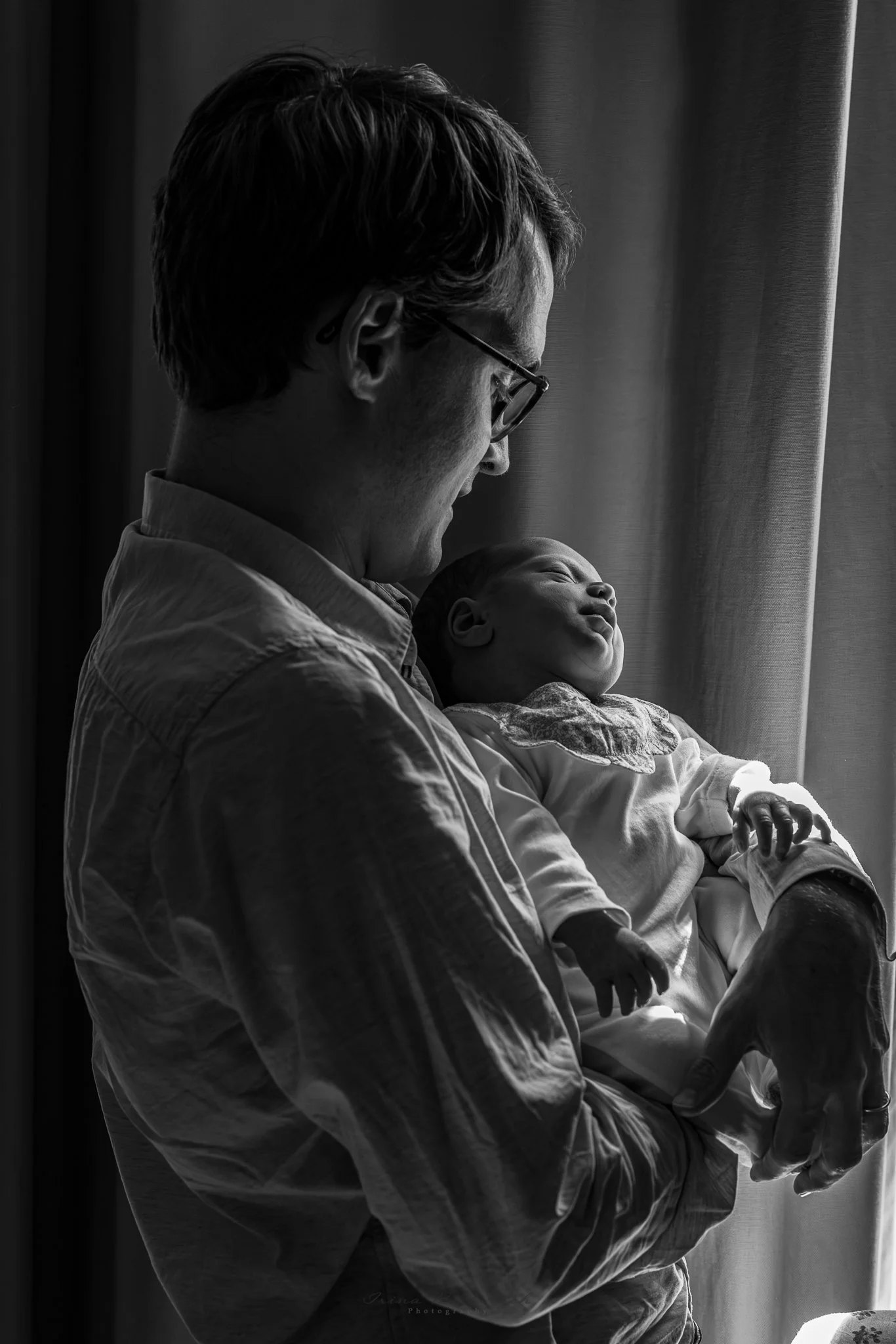 Jeune père porte dans ses bras et regarde son bébé