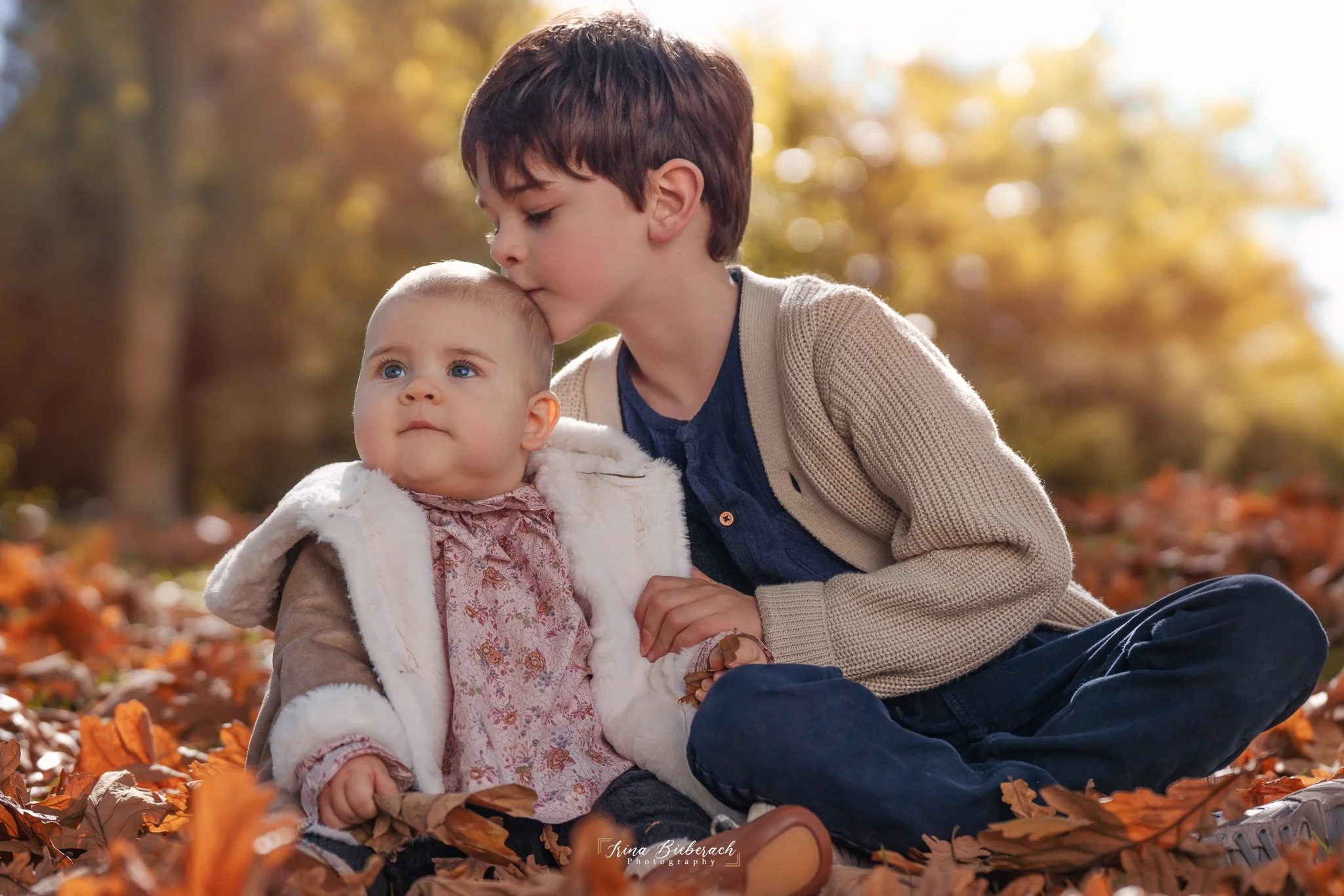 Enfant embrasse doucement sa petite soeur dans un parc pendant une journée d automne à Paris
