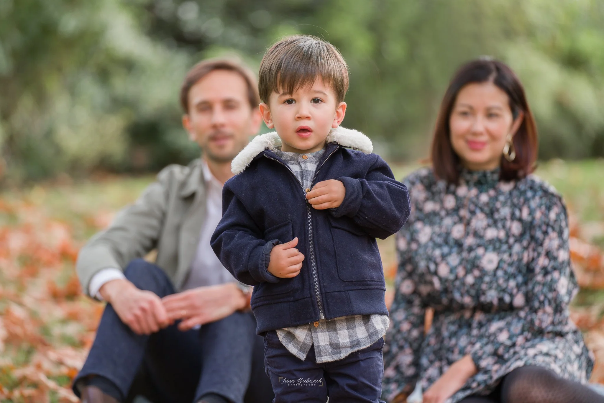 Petit garçon regarde attentivement et ses parents assis derrière le regardent 
