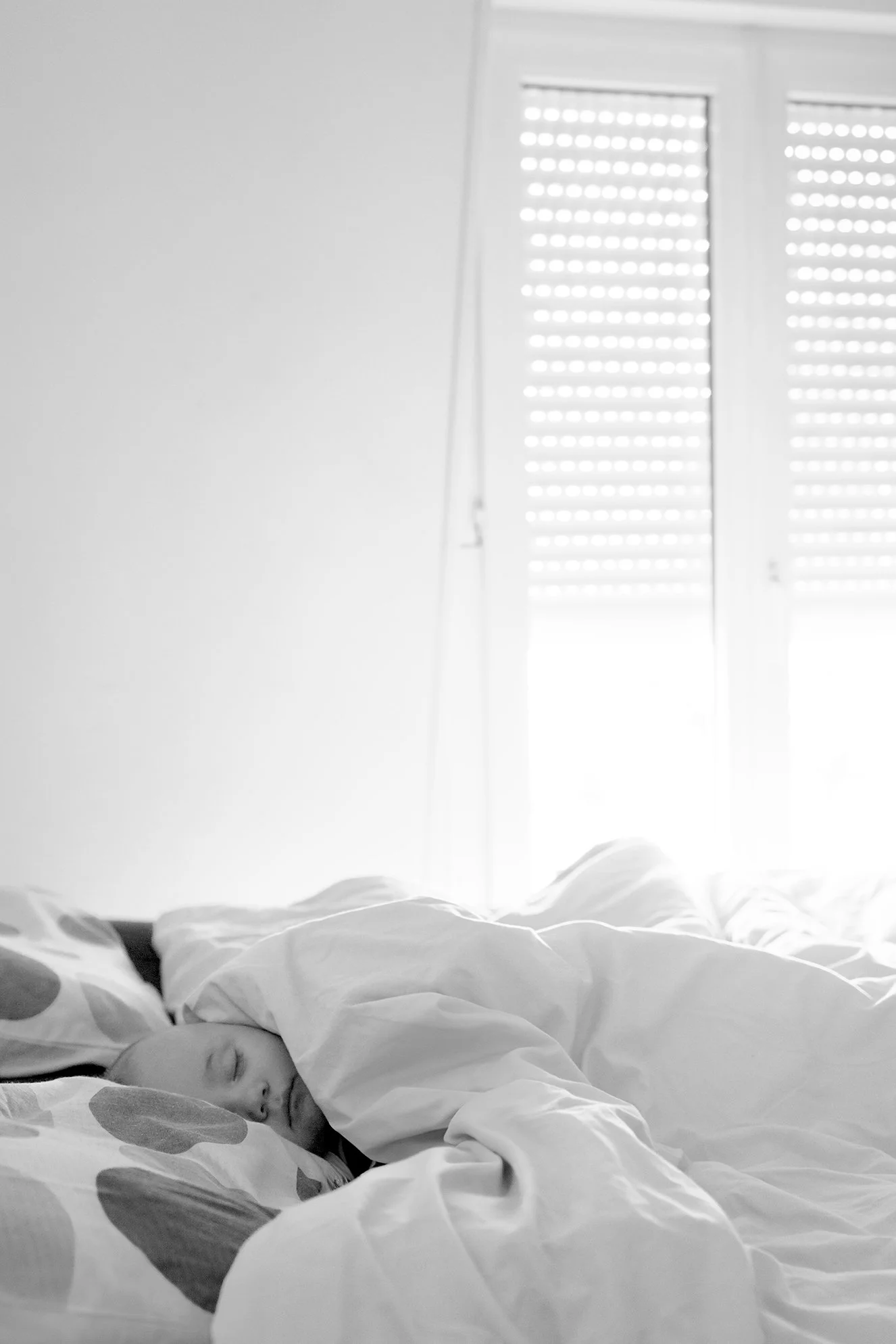 Bébé fait une sieste entre les couvertures du grand lit parental 