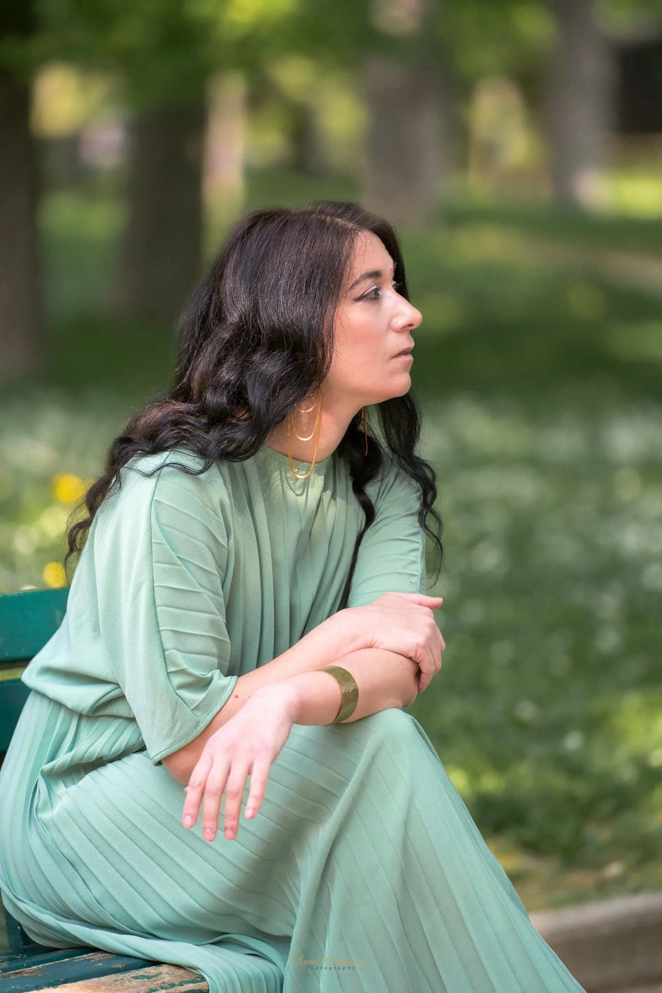 Profil gracieux d'une femme habillée en vert regardant l'horizon dans un parc verdoyant 
