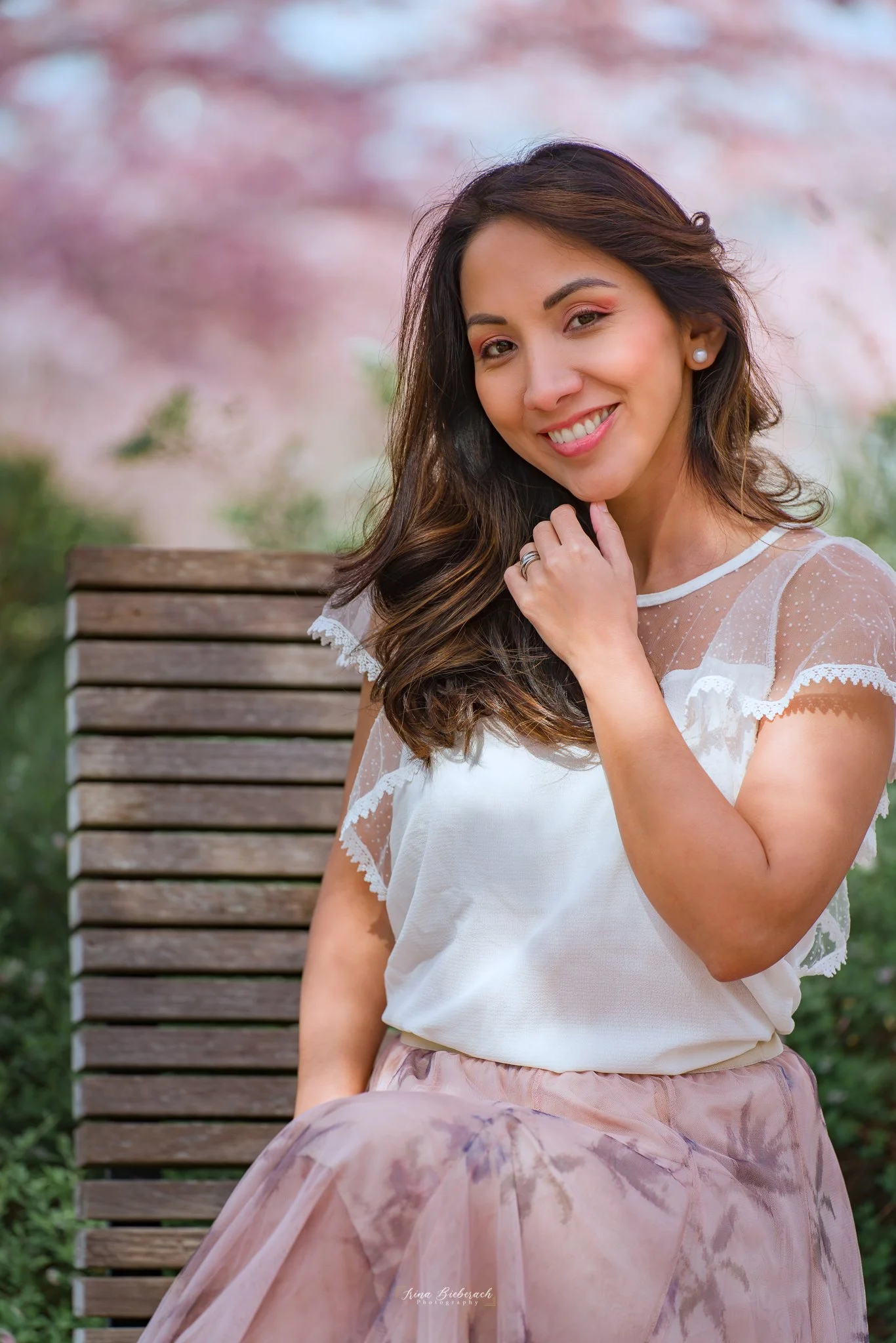 Femme souriante  assise regarde l’objectif et touche son menton