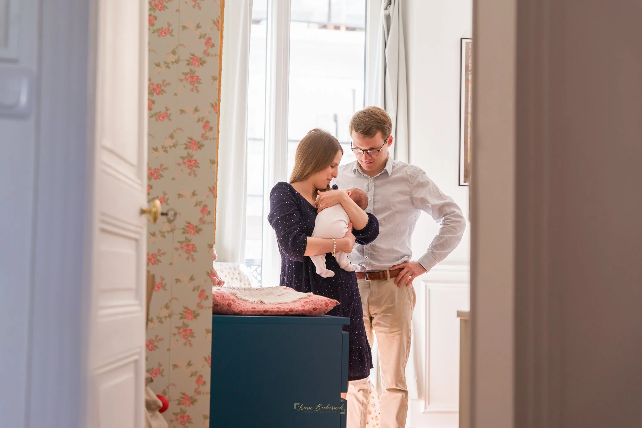 Nouveaux parents portent leur bébé près d'une fenêtre dans la chambre du bébé 