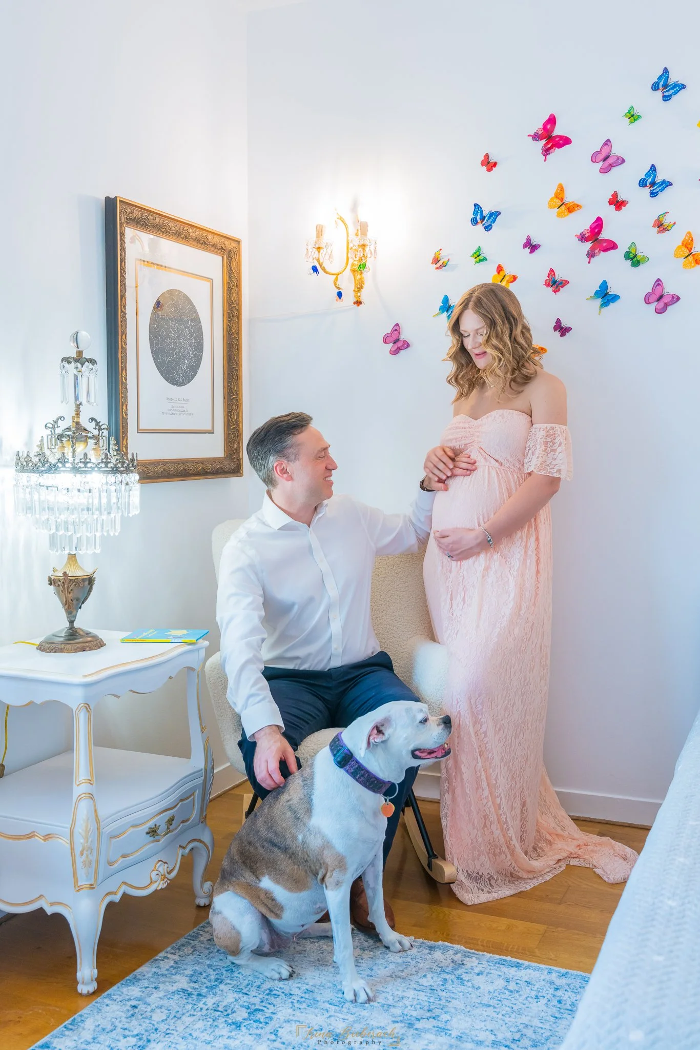 Couple de futurs parents avec leur chien dans une chambre élégamment décorée et baignée de lumière naturelle
