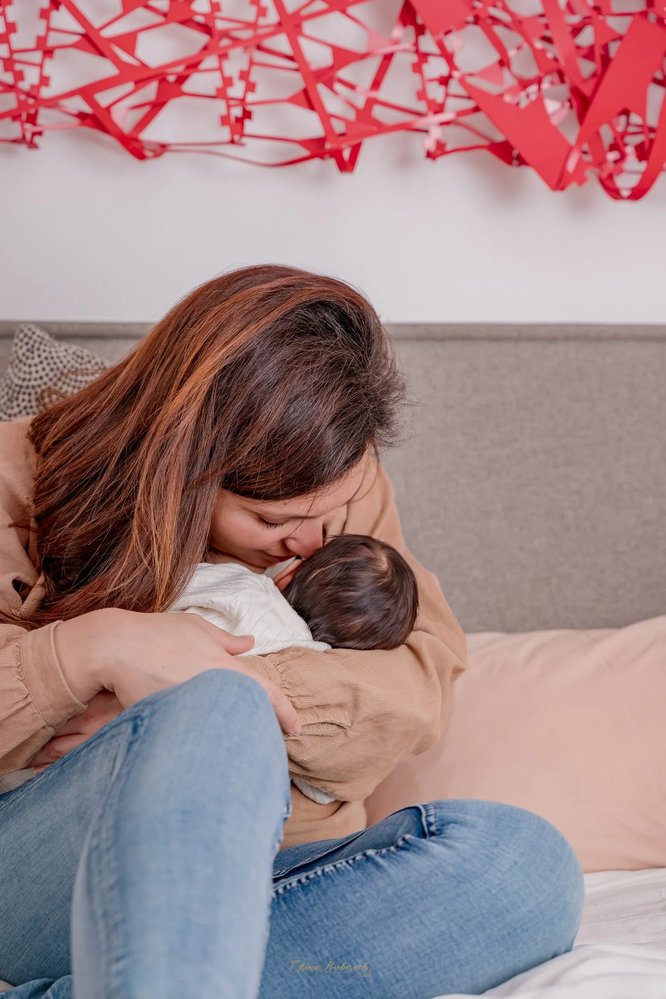 Femme s'approche du visage de son nouveau-né dans une chambre d’appartement à Paris