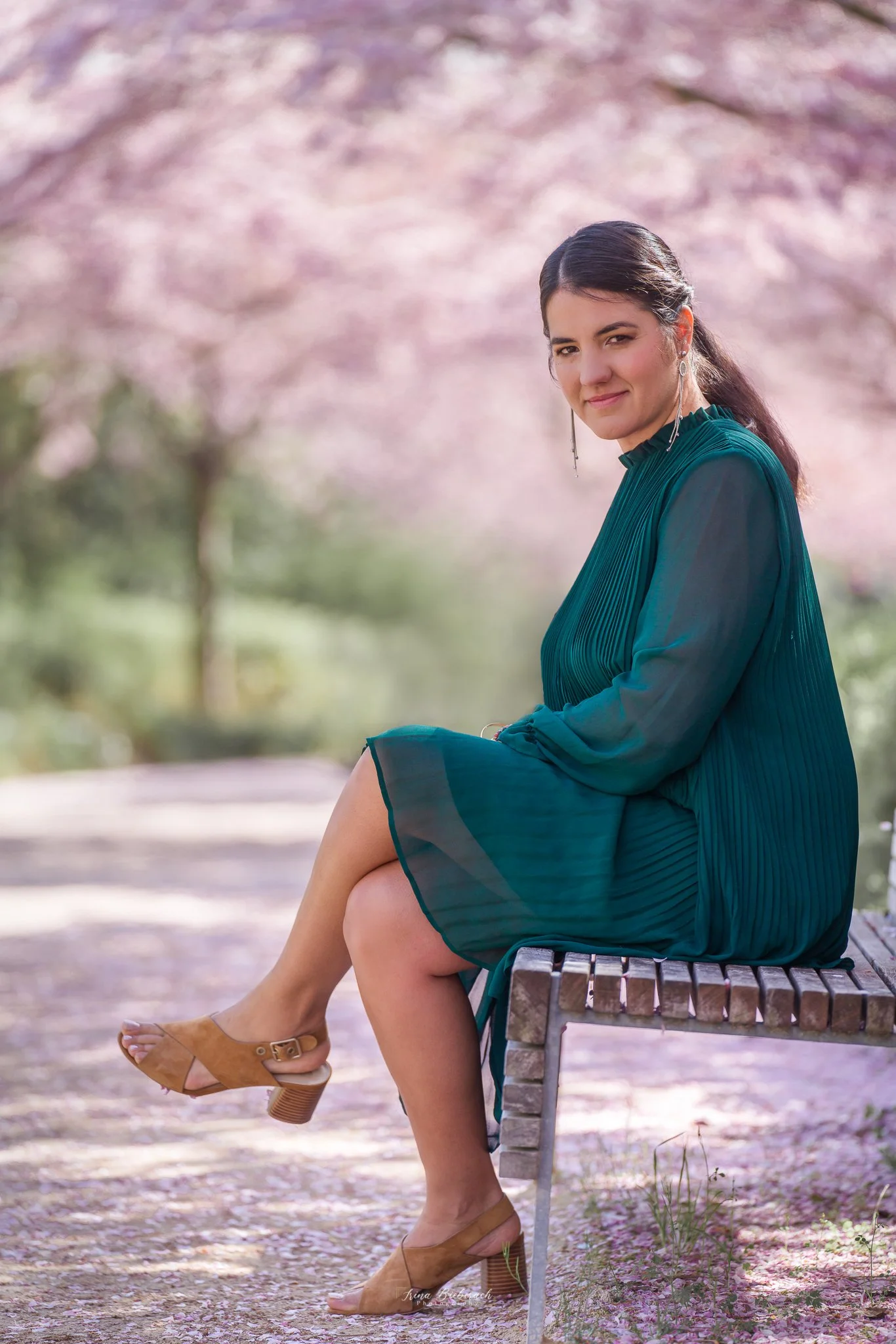 Femme habillée en vert assise dans une allée de cerisiers japonais fleuris au Parc Billancourt