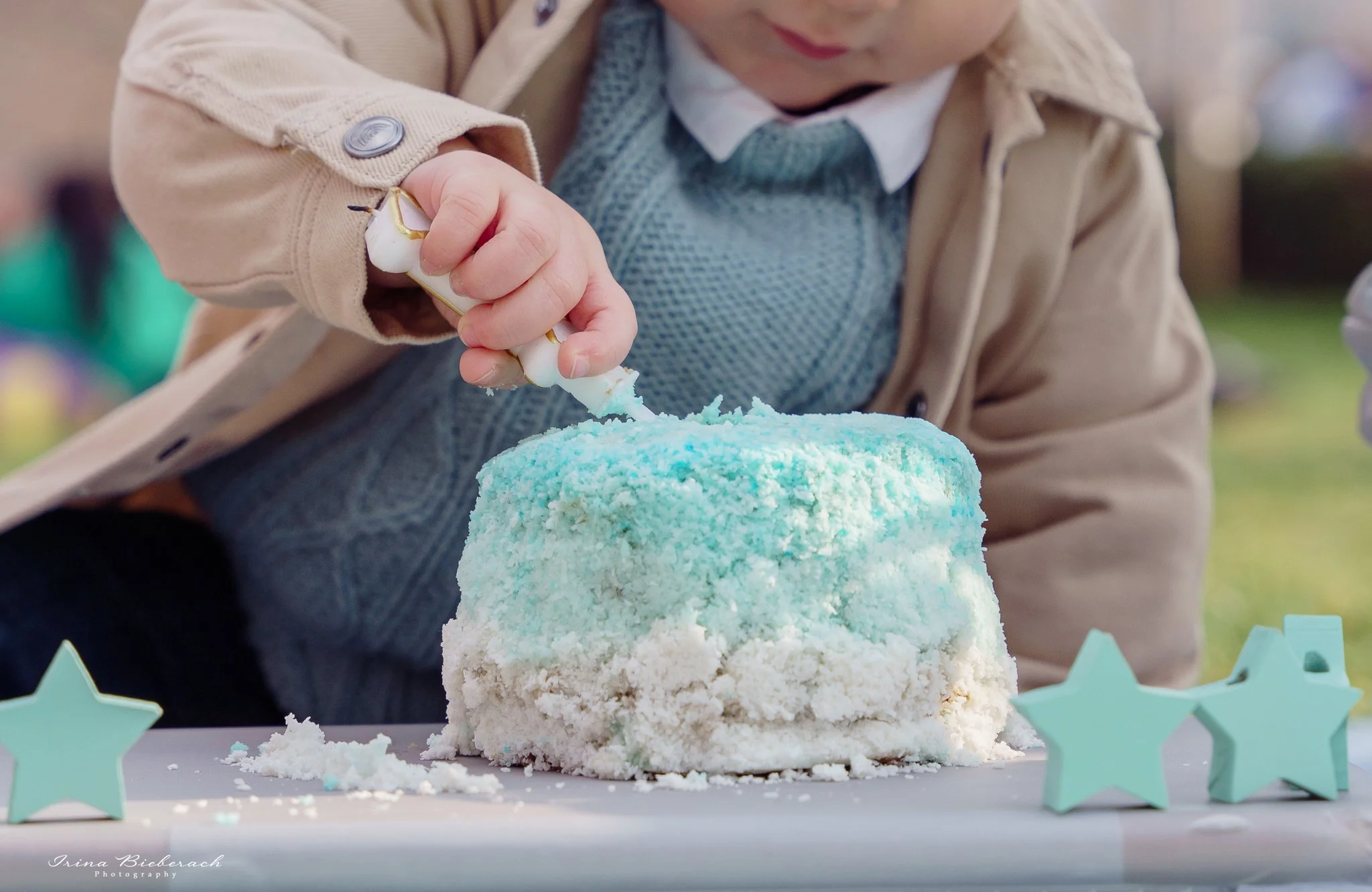 Mains d'un bébé qui détruit un petit gâteau d'anniversaire dans un parc parisien